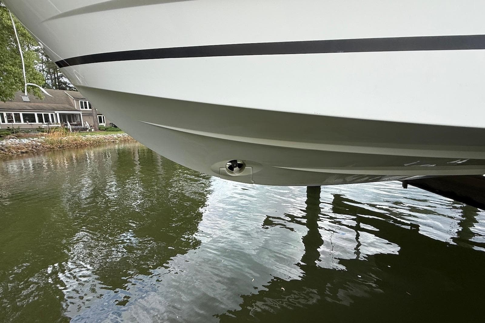 2017 Jeanneau NC 895 boat hull above water near a lakeside house.