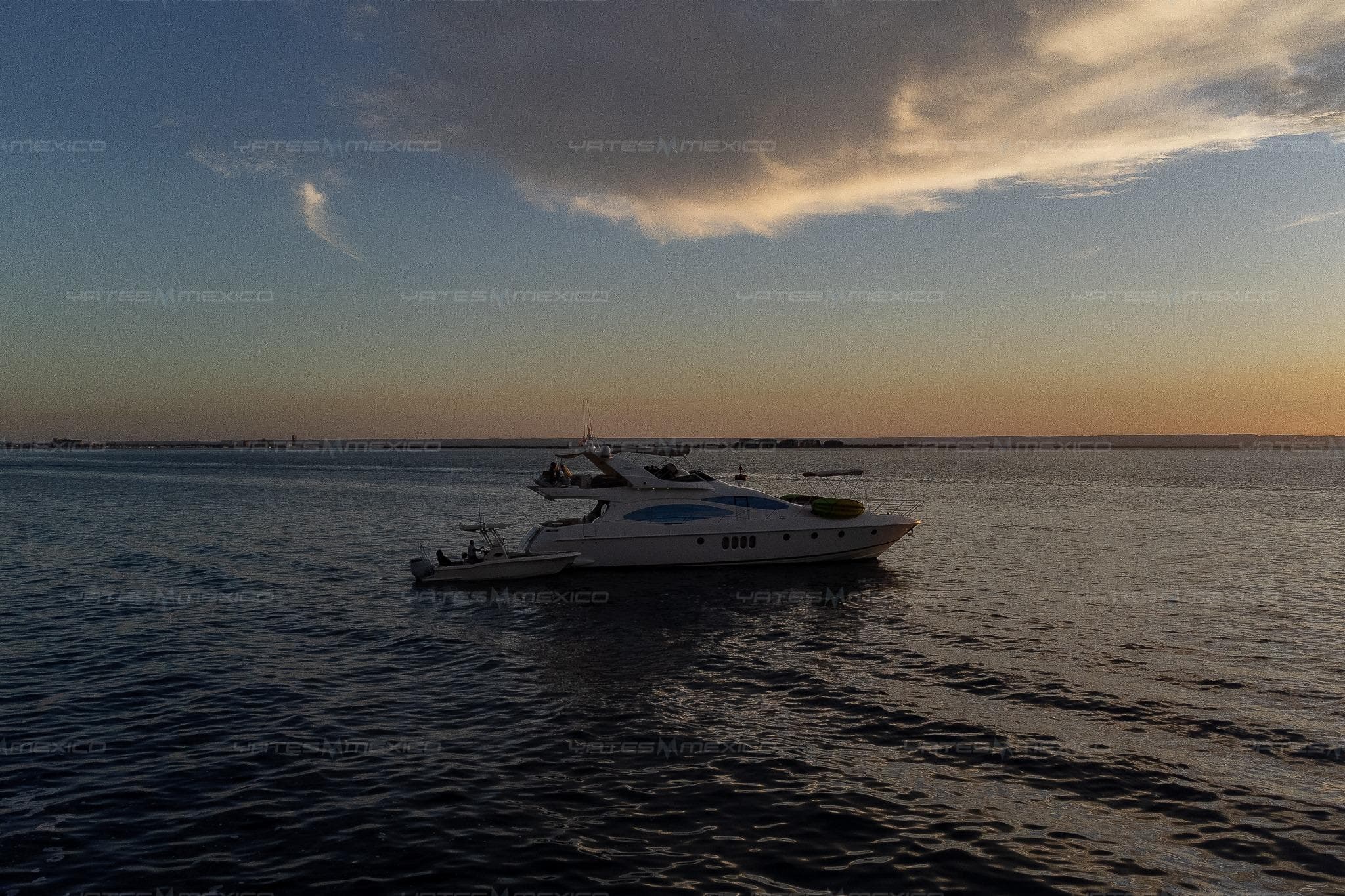 A 2004 Azimut 68 Plus yacht cruising at sunset on calm waters.