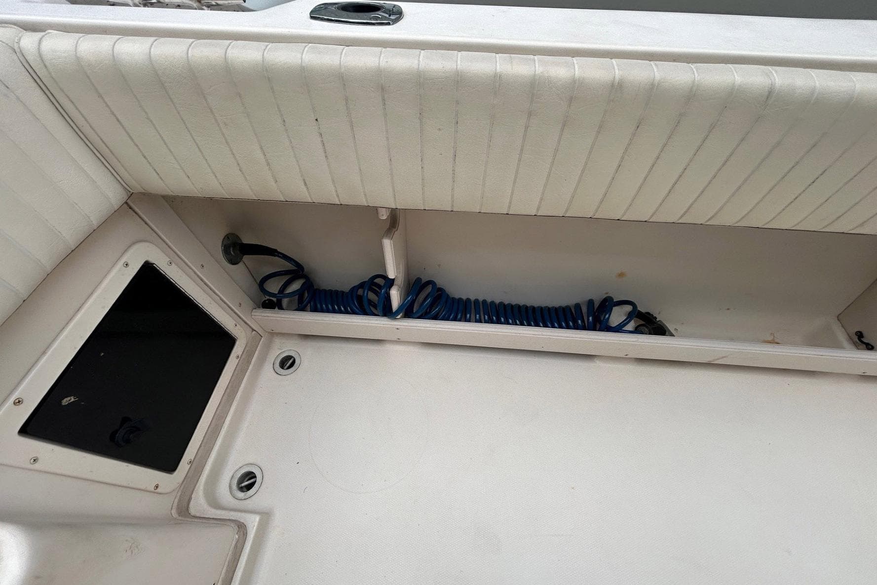 2004 Grady-White Gulfstream 232 boat interior with coiled blue hose and storage compartment.