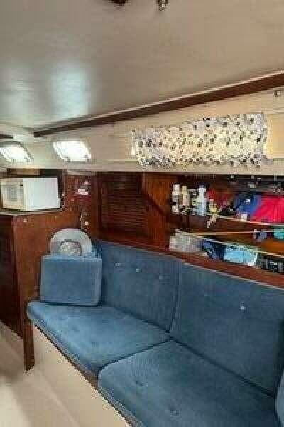 Interior of a 1988 Catalina 30 sailboat with blue seating and wooden cabinetry.