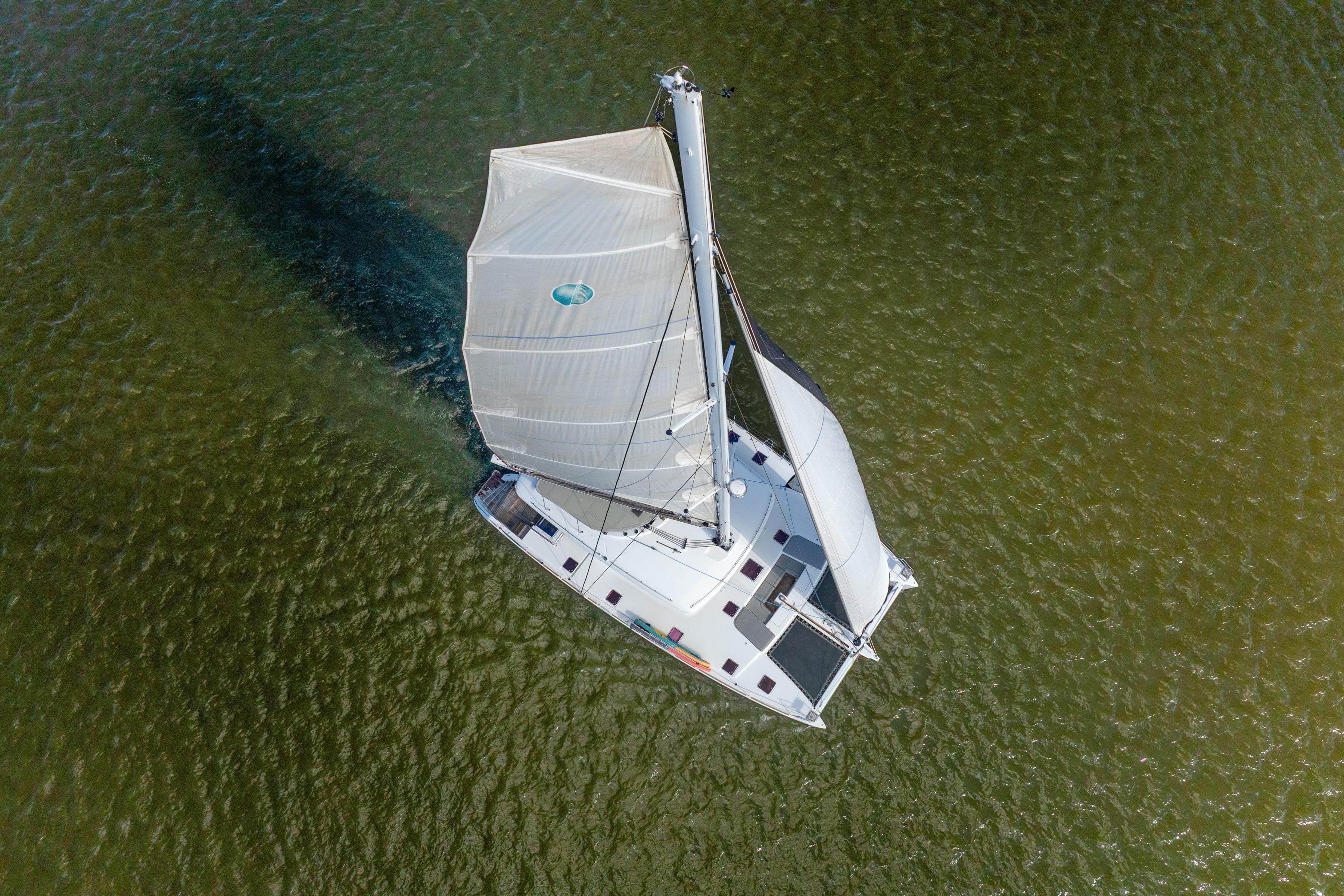 Aerial view of 2012 Lagoon 560 catamaran sailing on green water.