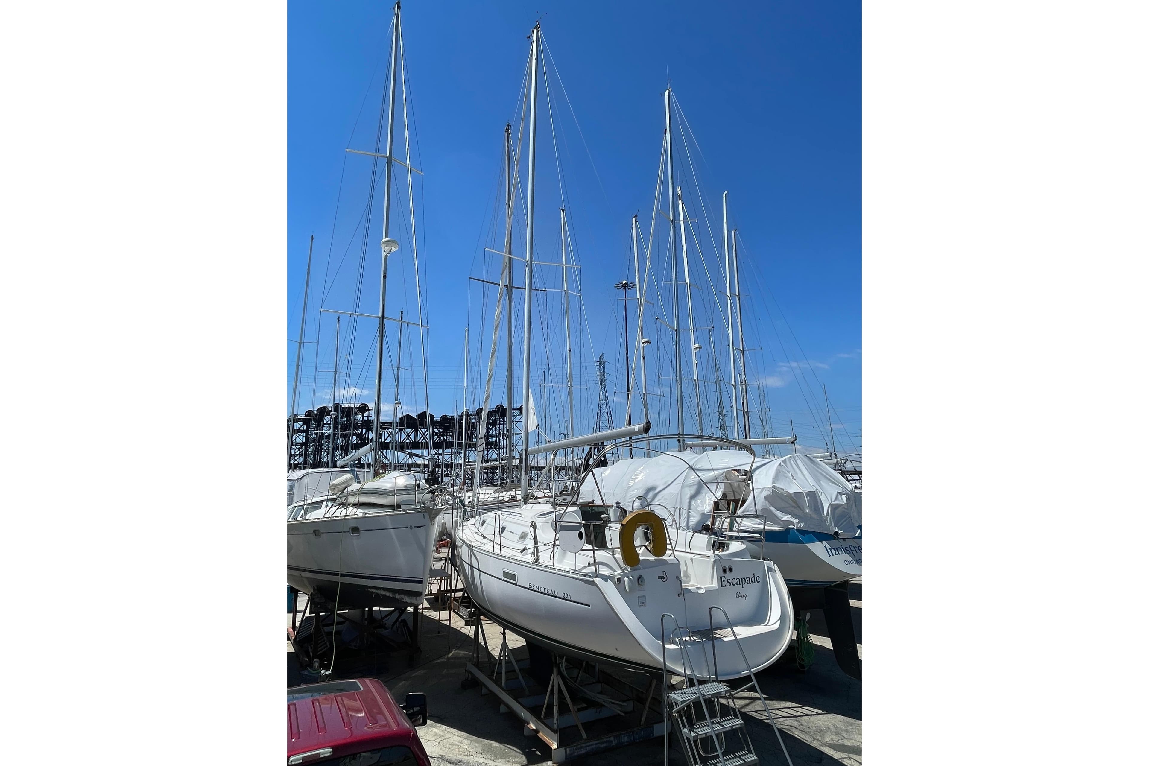 2002 Beneteau 331 sailboat in a marina, surrounded by other boats under a clear blue sky.