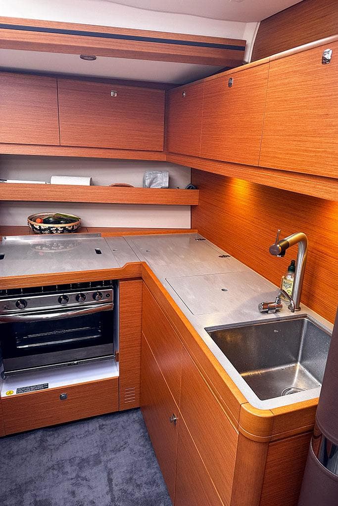 Modern kitchen in 2021 Dufour 56 yacht with wood cabinetry and stainless steel appliances.