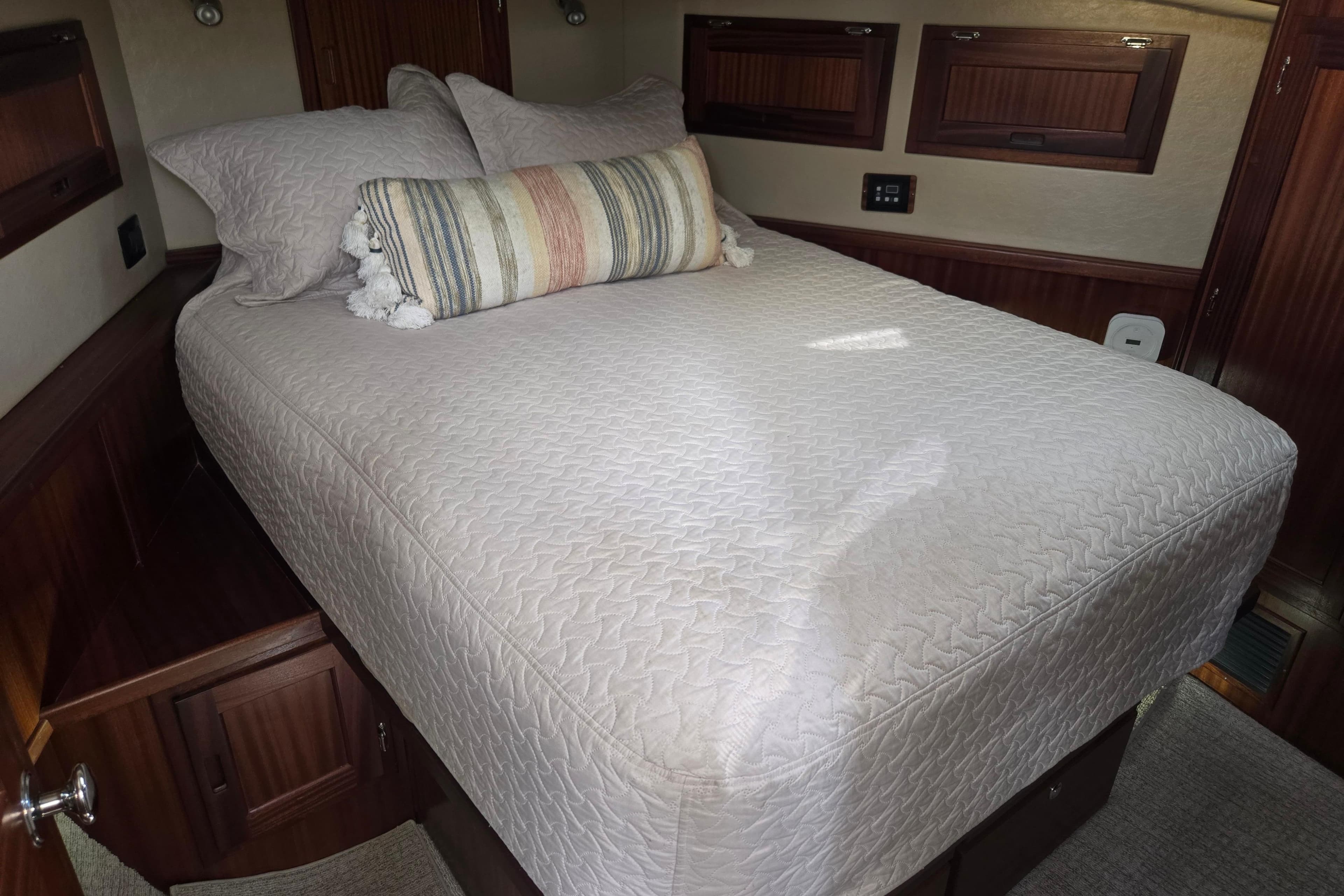 Cozy bedroom interior of 2012 American Tug 365 Flybridge with elegant bedding and wood accents.