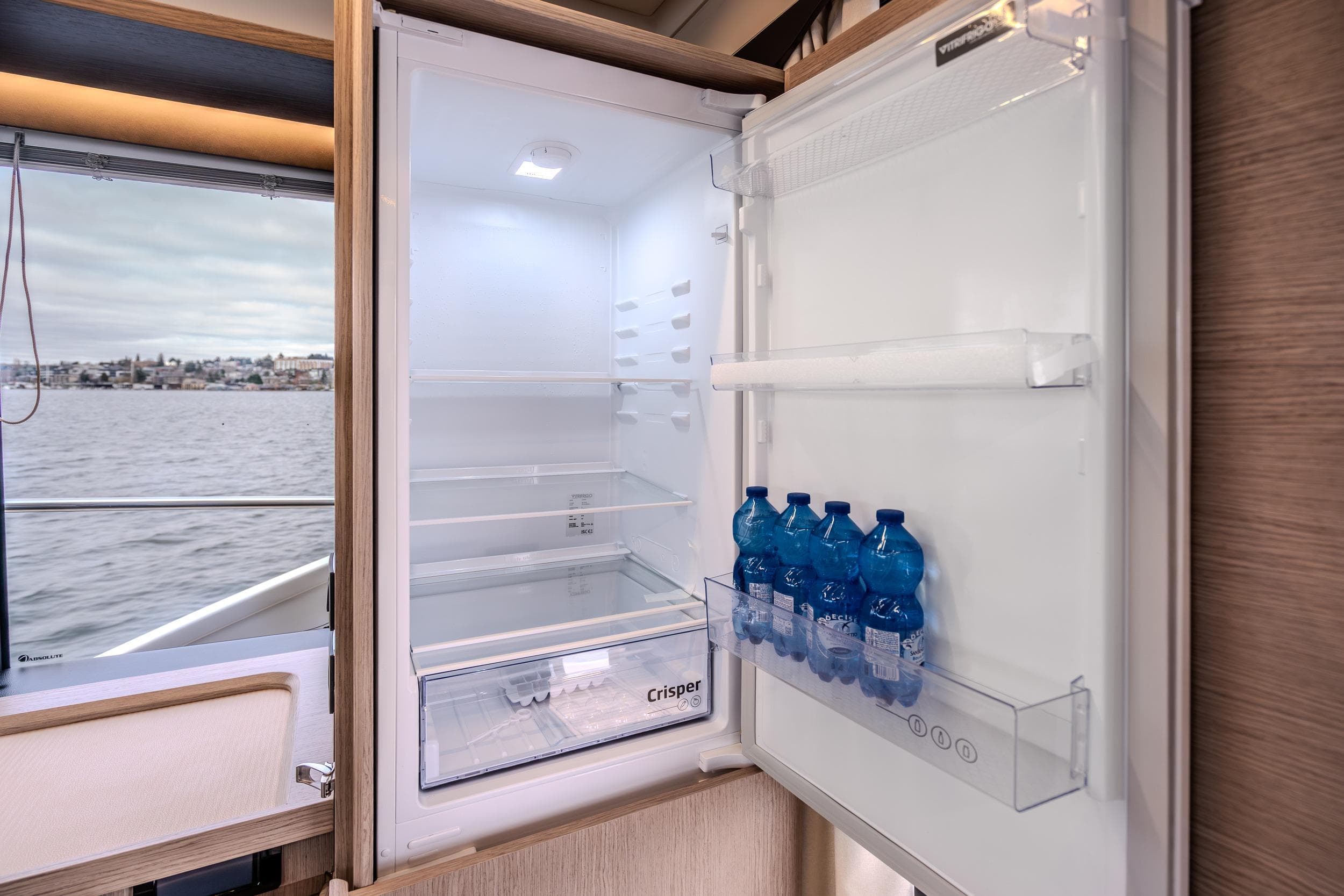 Open fridge with water bottles inside, aboard 2026 Absolute 48 Coupe yacht.