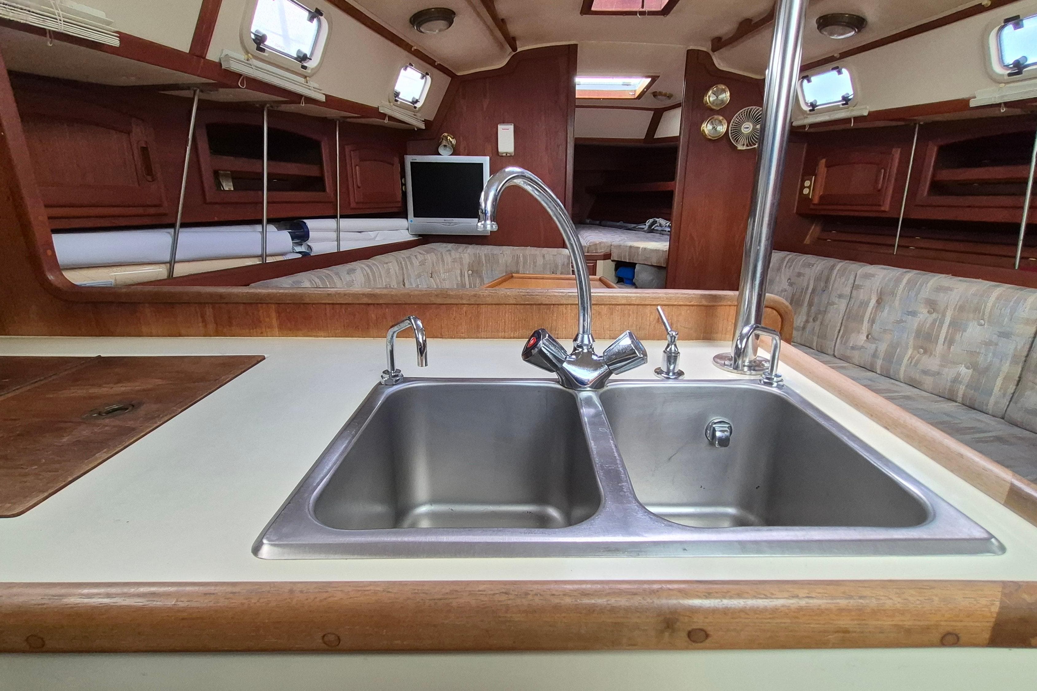 Interior of a 1991 Ericson 38 sailboat featuring a dual sink and cozy seating area.