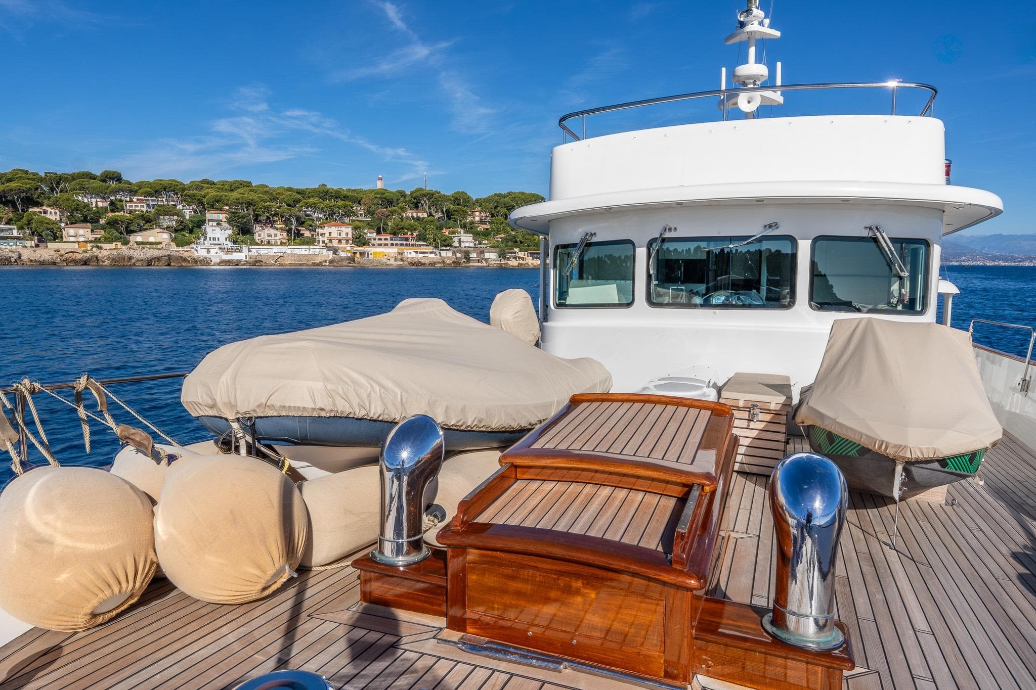 Vintage 1969 Feadship 25.8m yacht deck with scenic coastal backdrop.