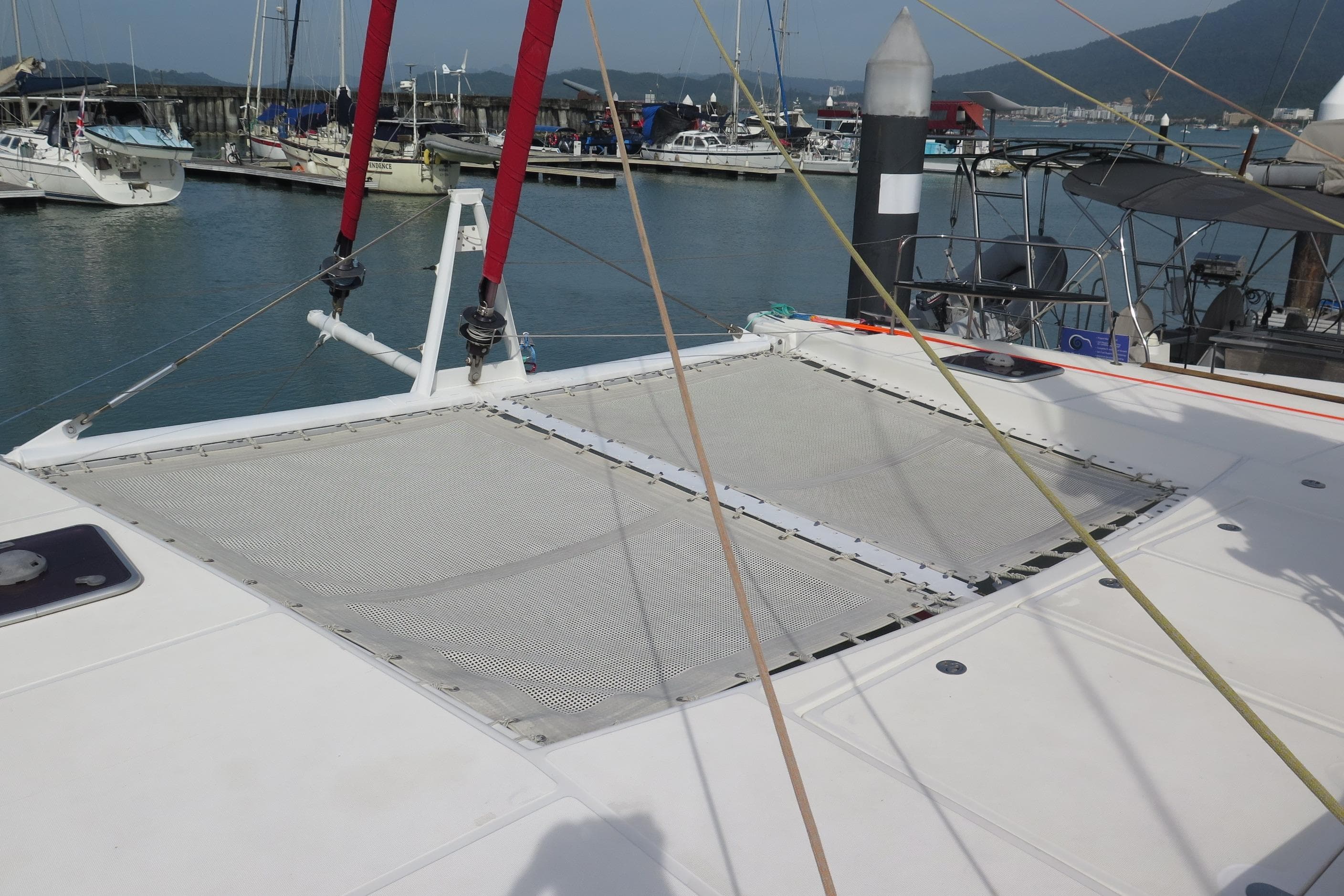 Catana 47 catamaran (2011) docked at marina, featuring netted deck area.