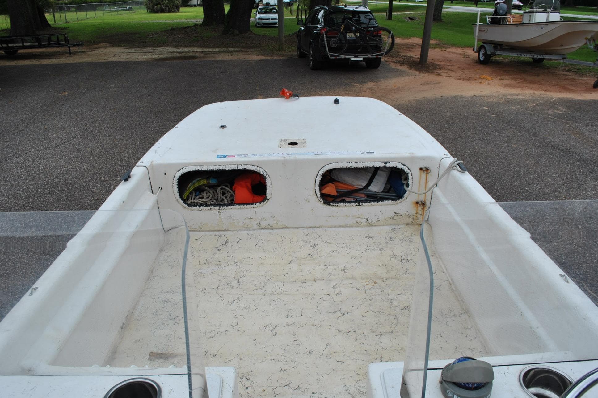 1999 Carolina Skiff 19 Classic boat interior with storage compartments at a parking area.