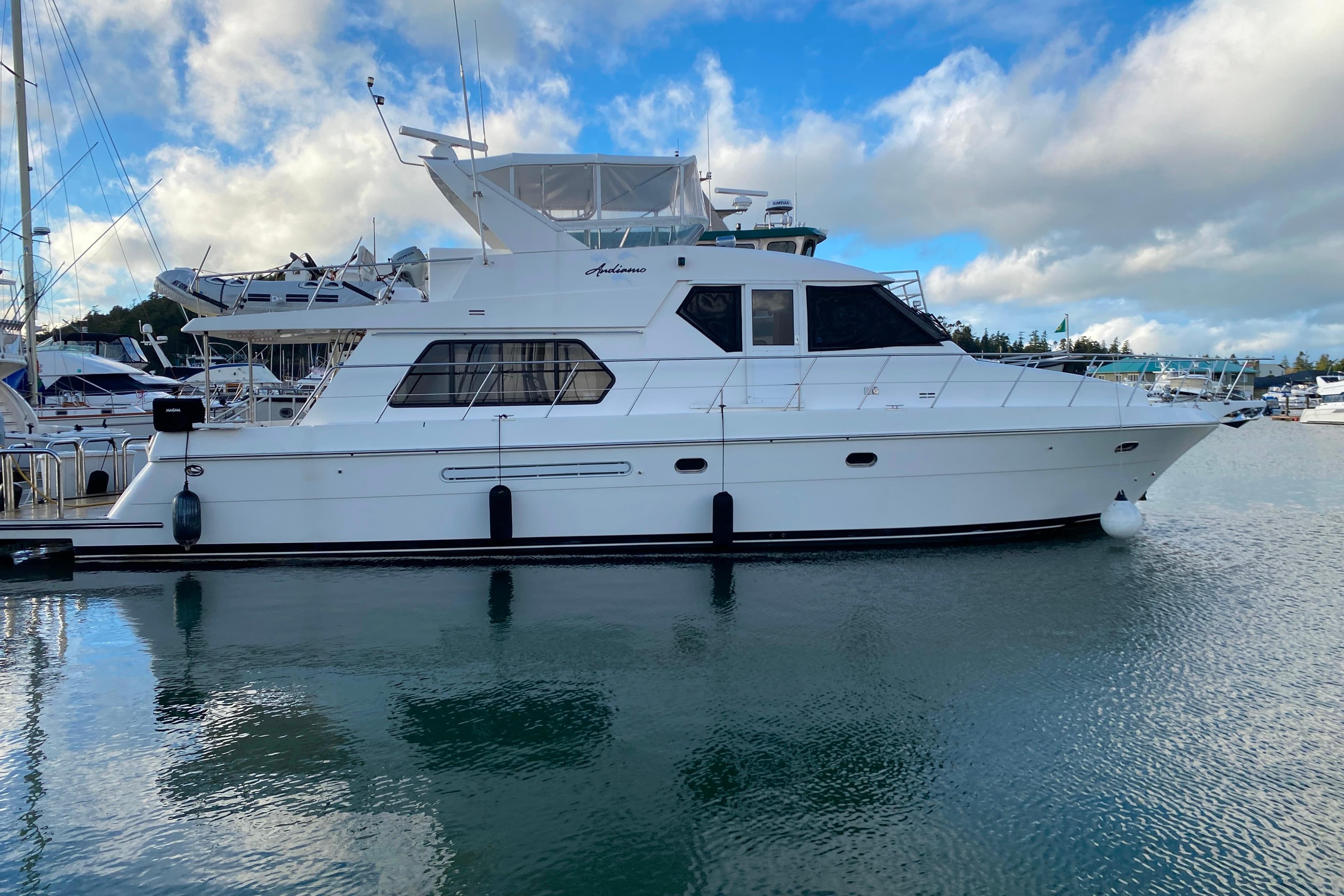 White 2001 Compass 57 yacht docked in marina under blue sky.