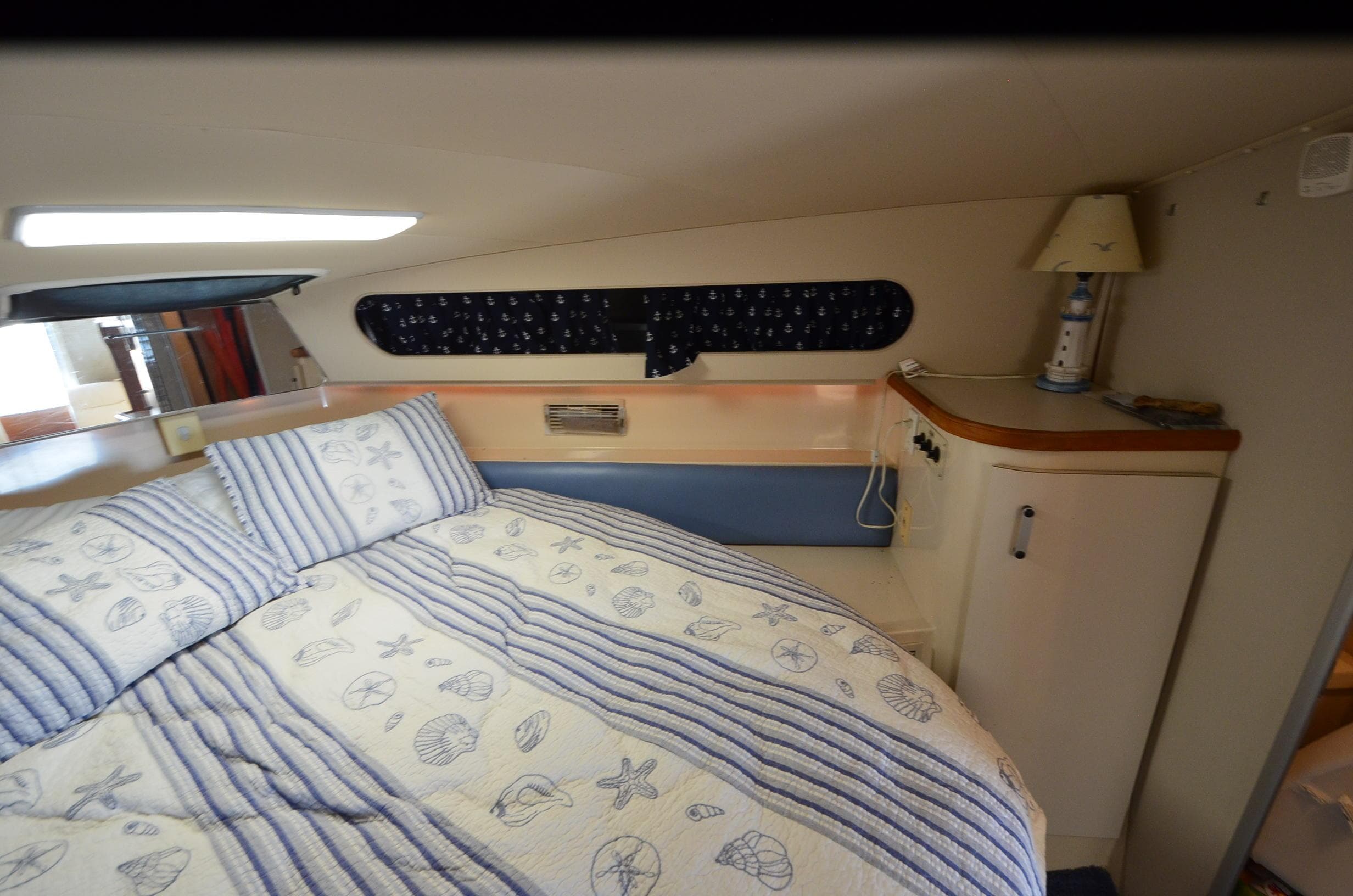 Cozy cabin interior of 1989 Carver SANTEGO with nautical-themed bedding and decor.
