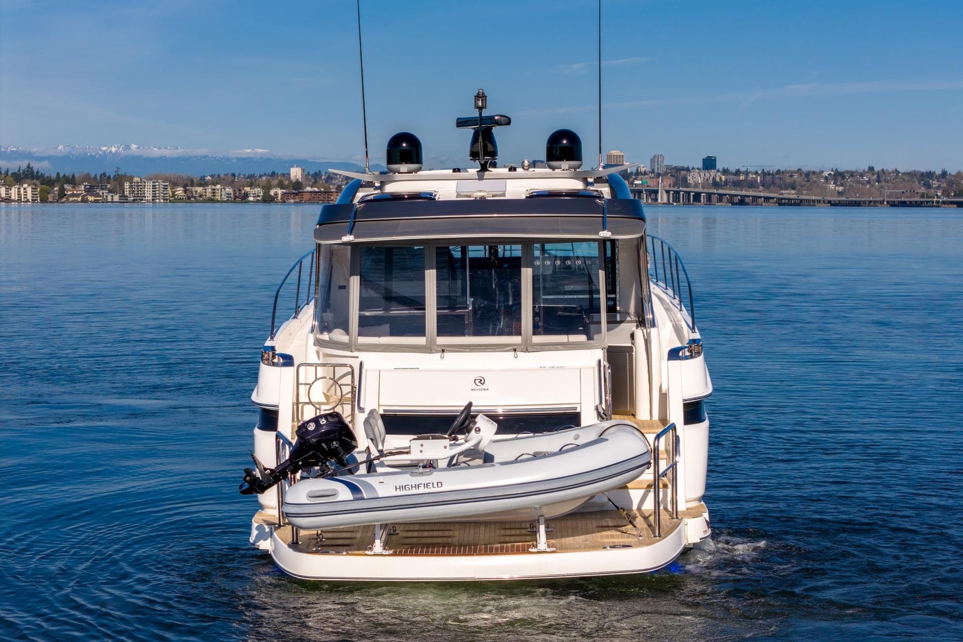 2023 Riviera 4600 Sport Yacht Platinum Edition on calm water, rear view with tender.