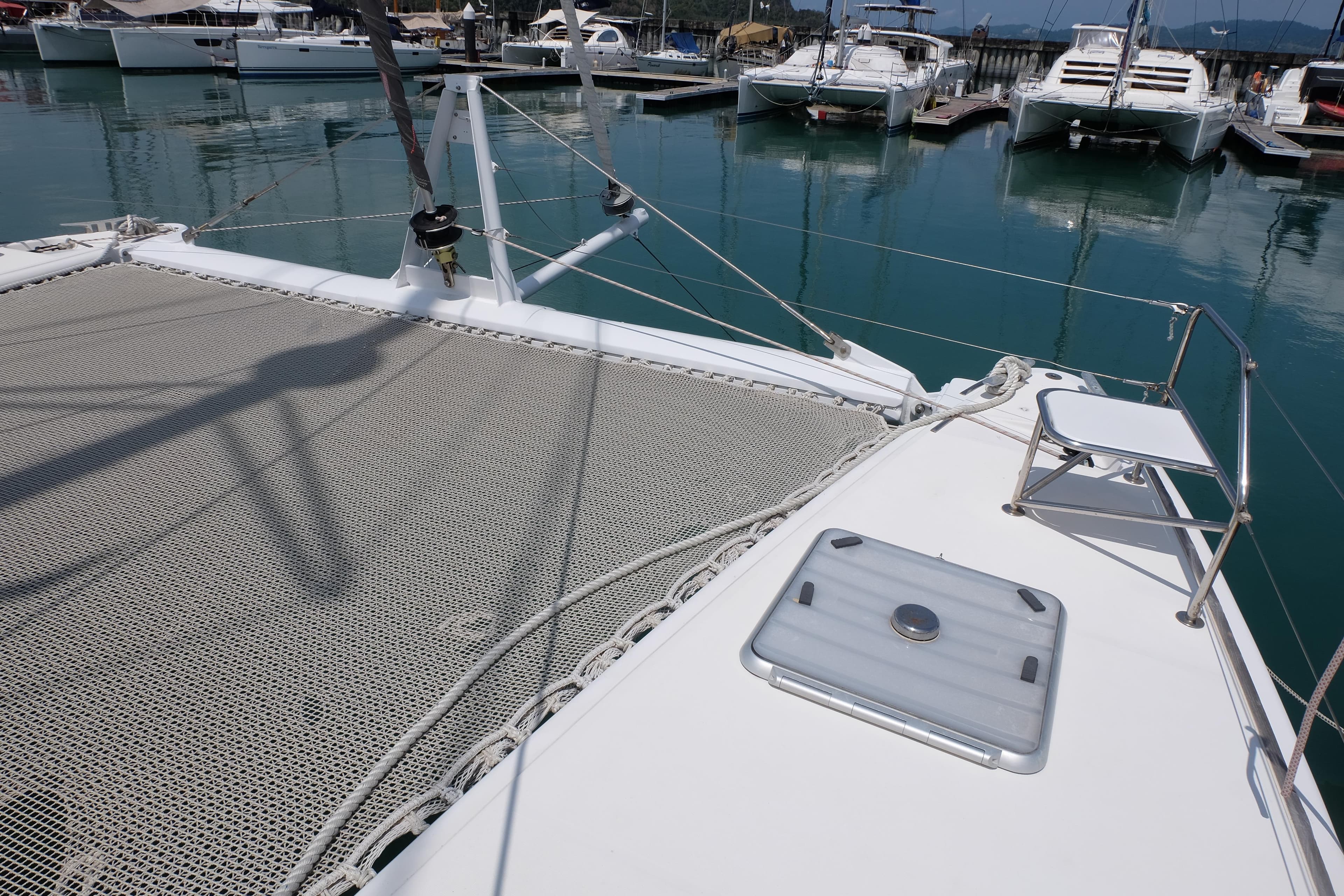 Catana 471 catamaran deck, 2002 model, docked in a marina with calm waters.