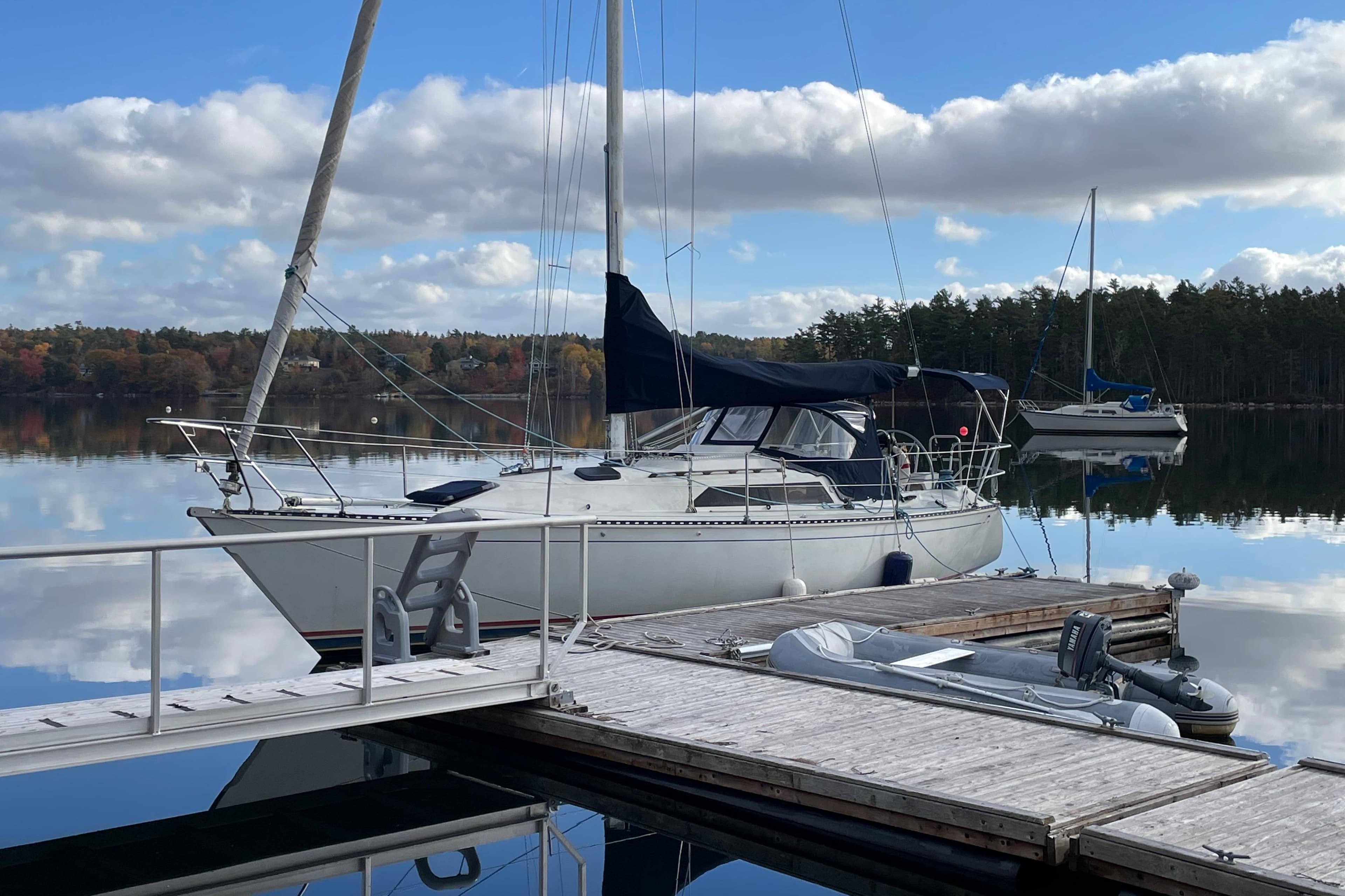1985 C&C 33 MK 2 sailboat docked on calm lake with cloudy sky.