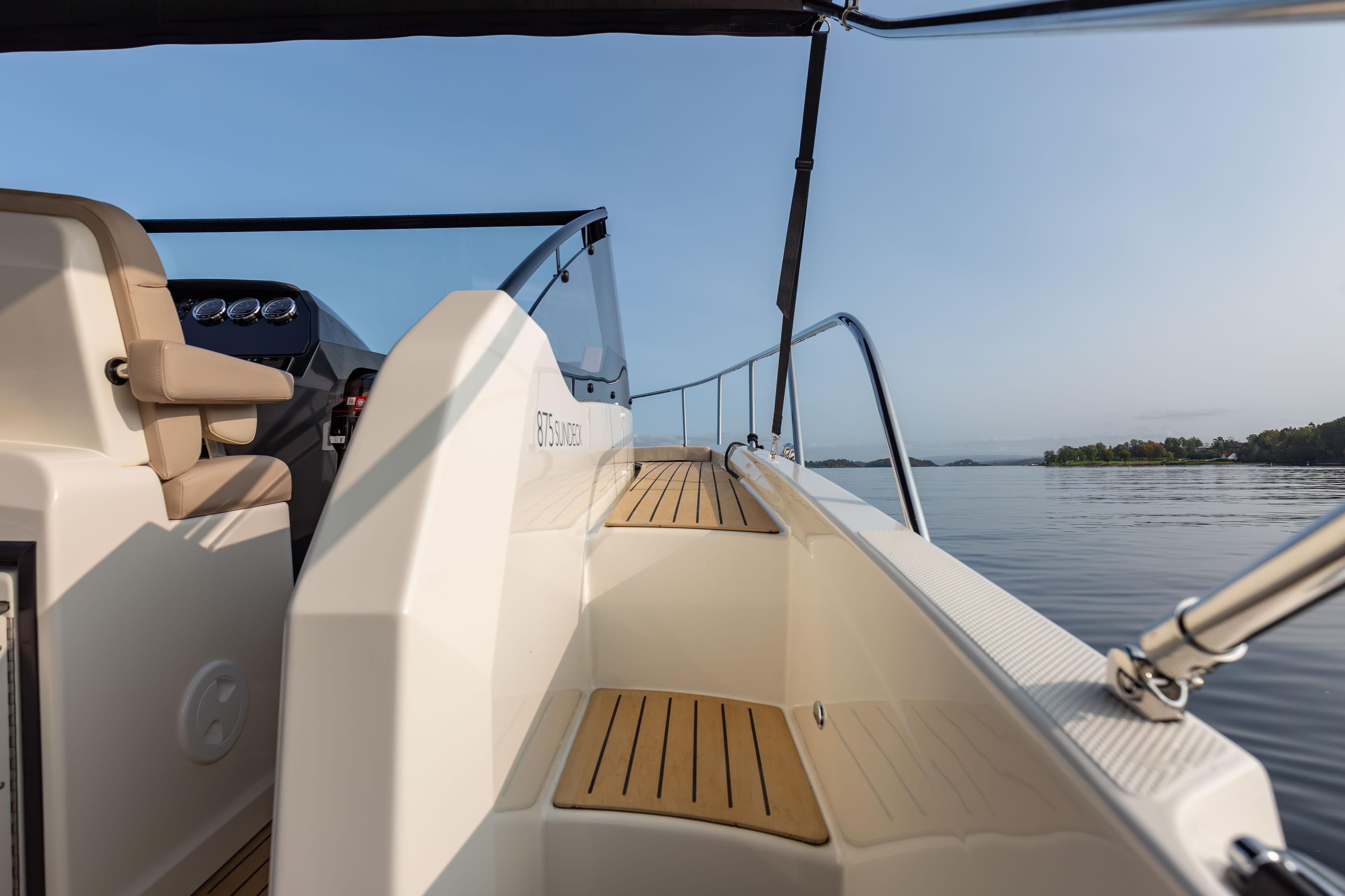 2024 Quicksilver Activ 875 Sundeck boat on calm water, showcasing sleek design and spacious deck.