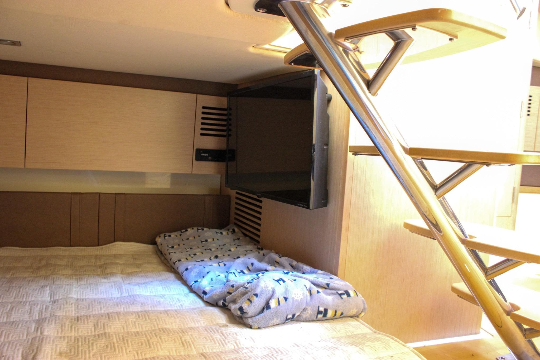 2017 Chris-Craft Launch 38 cabin interior with bed, TV, and modern staircase.