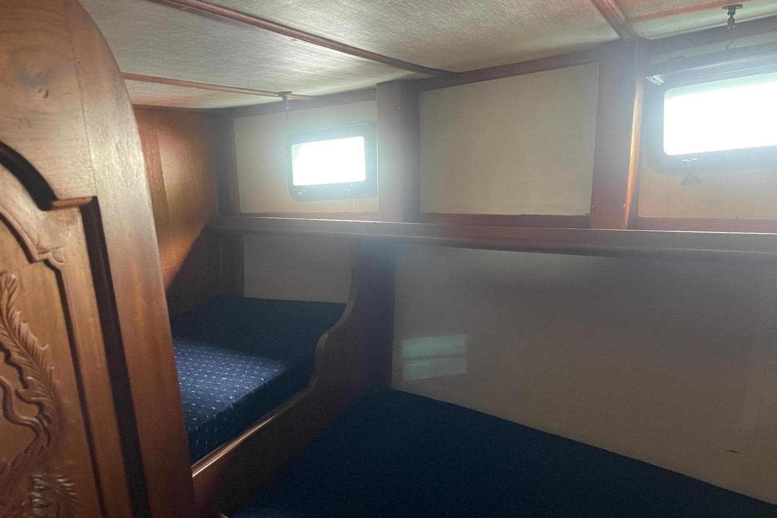 Cozy cabin interior of 1980 Island Trader 46 sailboat with wooden accents and small windows.