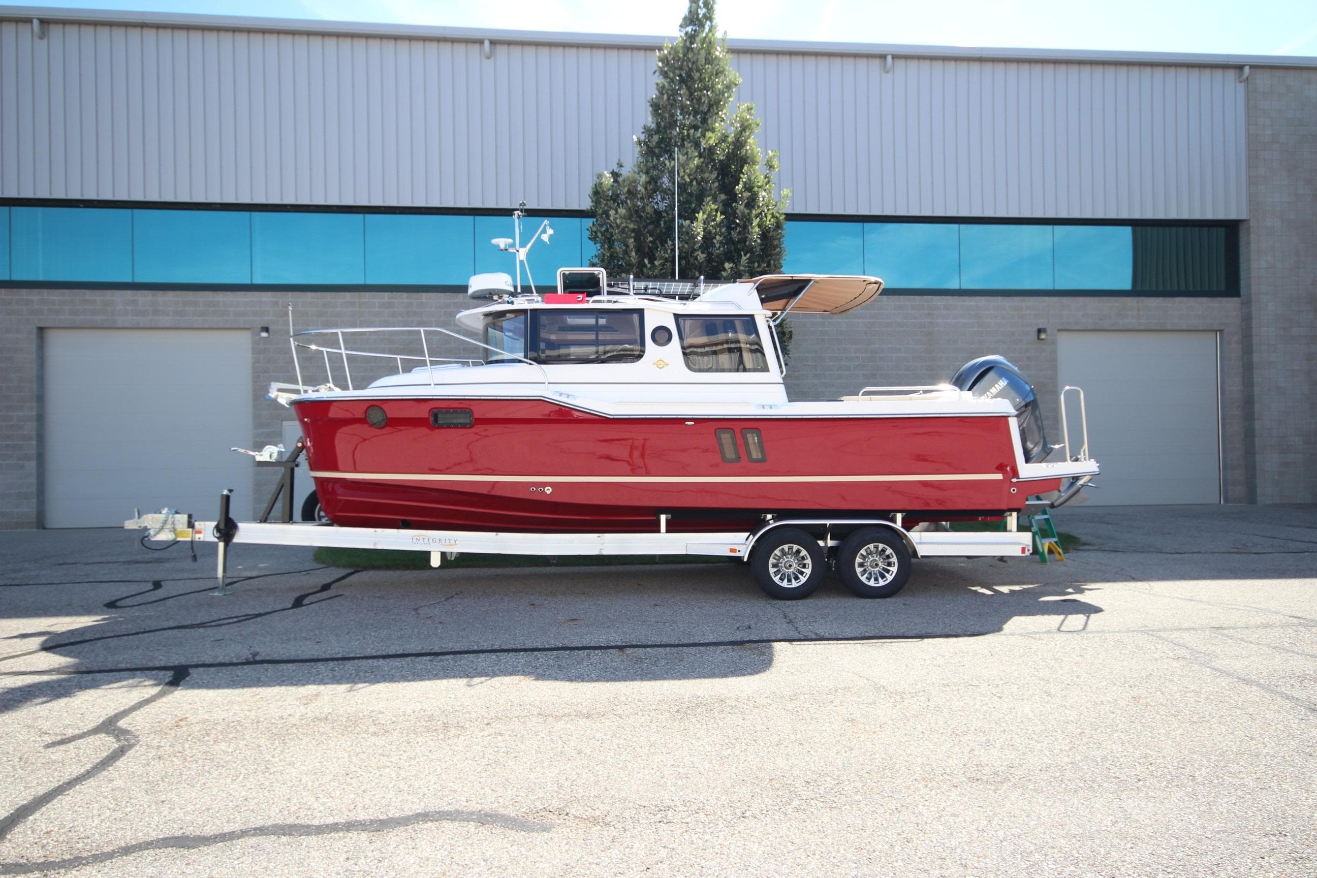 2025 Ranger Tugs R-25 Luxury Edition boat on trailer, parked outside industrial building.
