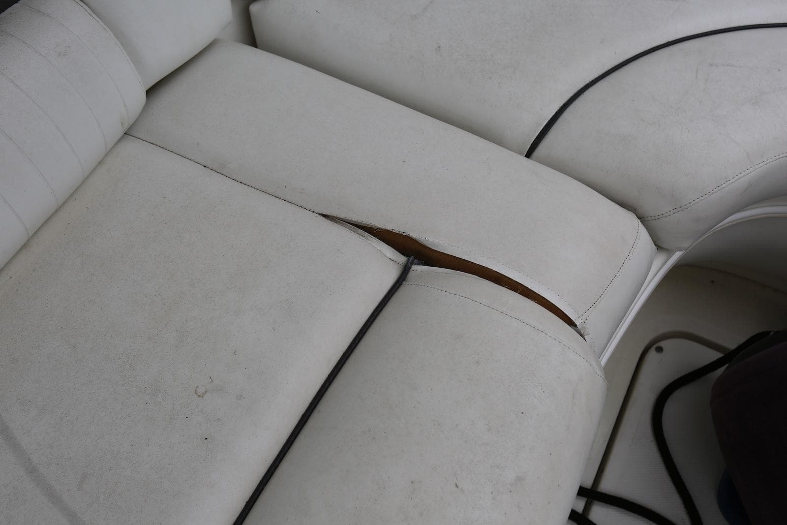 Torn white upholstery on 2003 Sea Ray 420 Sundancer boat seat.