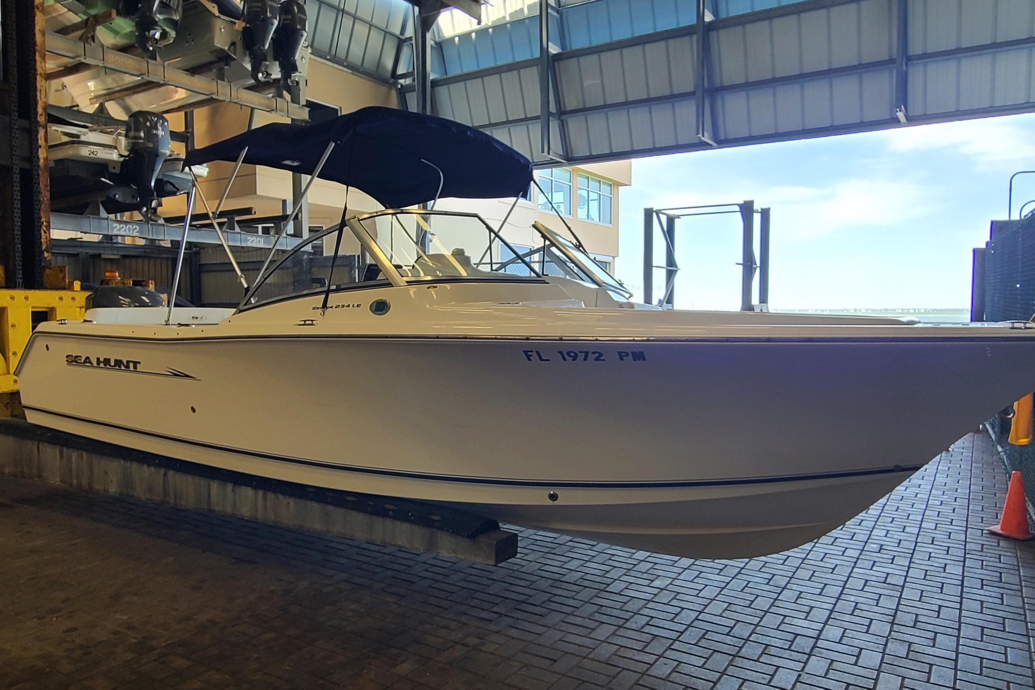 2013 Sea Hunt Escape 234 LE boat in storage facility, side view with canopy.