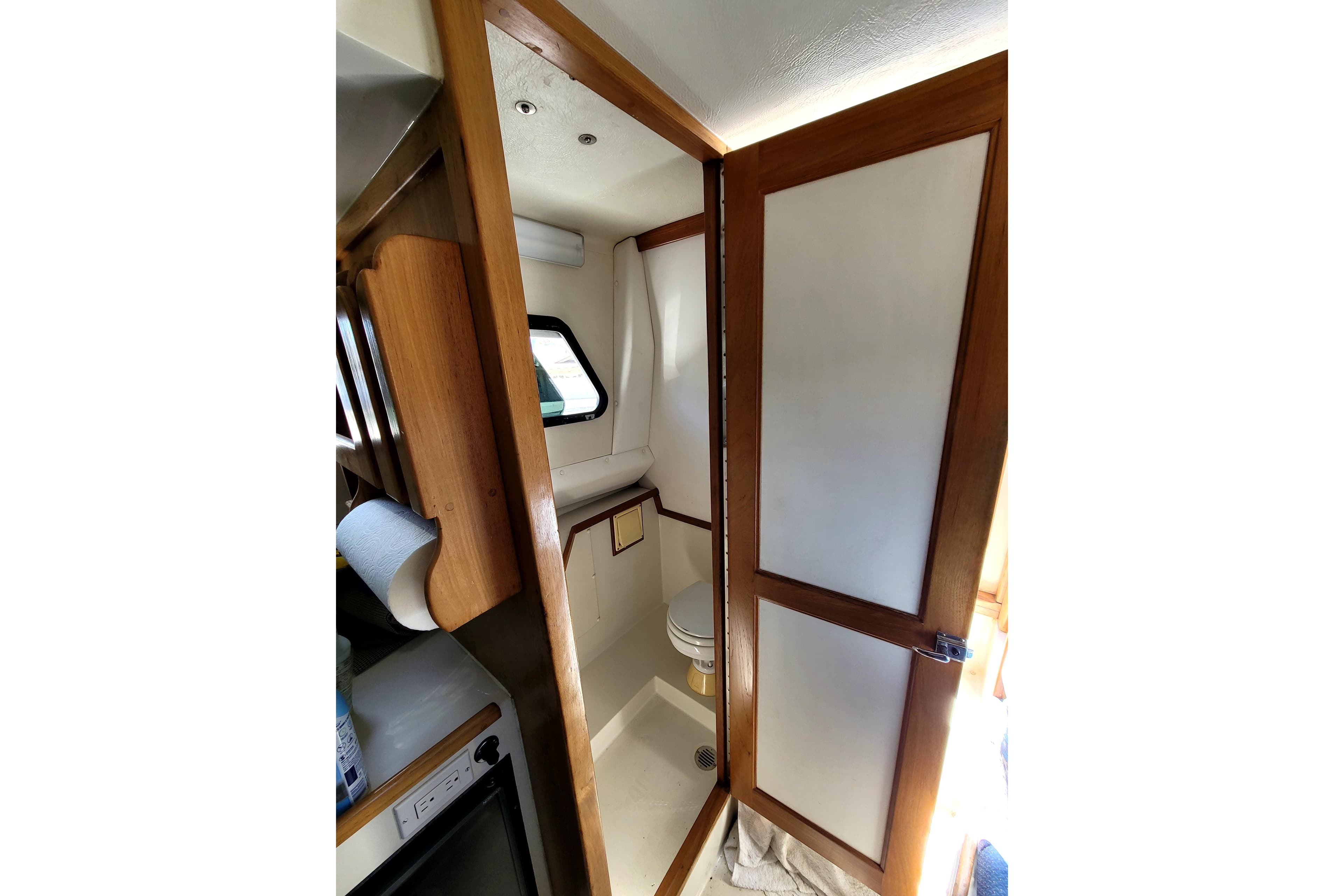 Interior of 2001 Skipjack 262 Flybridge boat, featuring a compact bathroom with wooden accents.