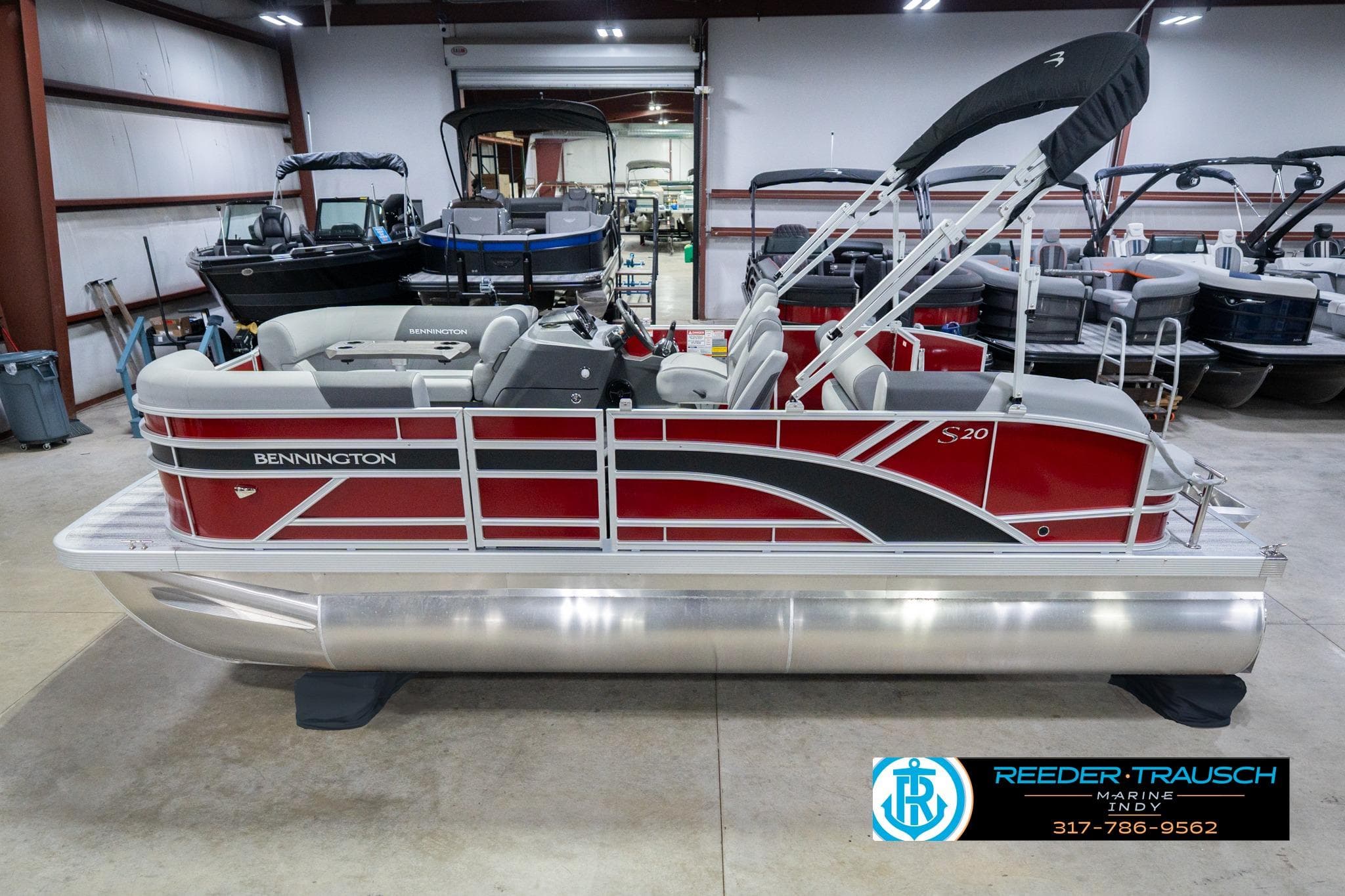 2026 Bennington 20 SSR pontoon boat in showroom, featuring sleek red and silver design.