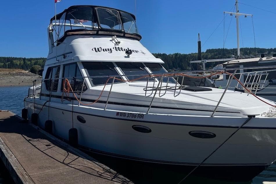 A white boat named "Way Maker" docked at a marina under a clear blue sky.