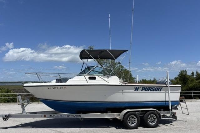 1989 Pursuit 2260 Denali boat on trailer under clear blue sky.
