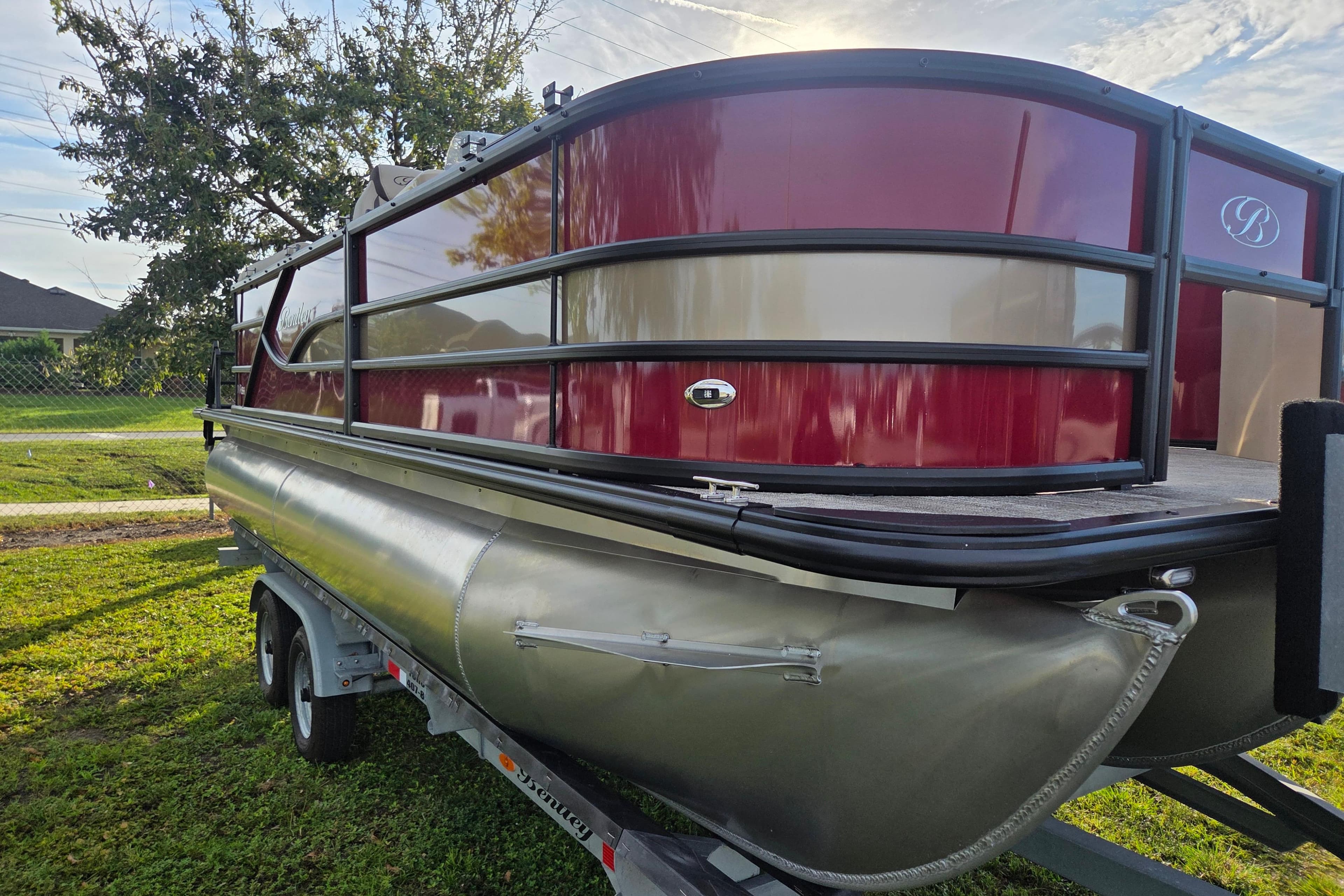 2026 Bentley Pontoons Fish 203 on trailer, red and silver design, parked on grass.