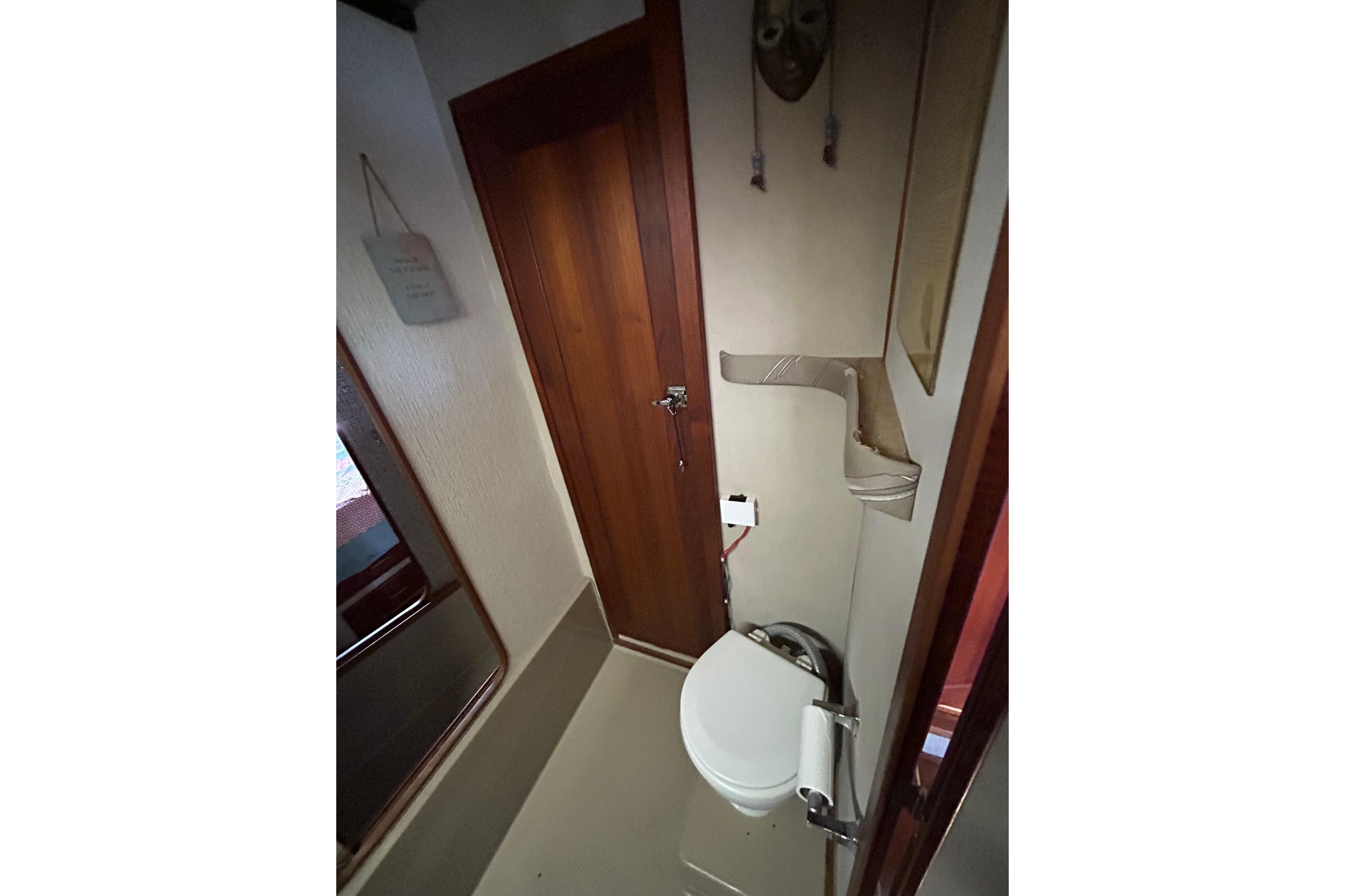 Bathroom interior of 1985 Bayliner 3870 Motoryacht, featuring wooden door and compact design.
