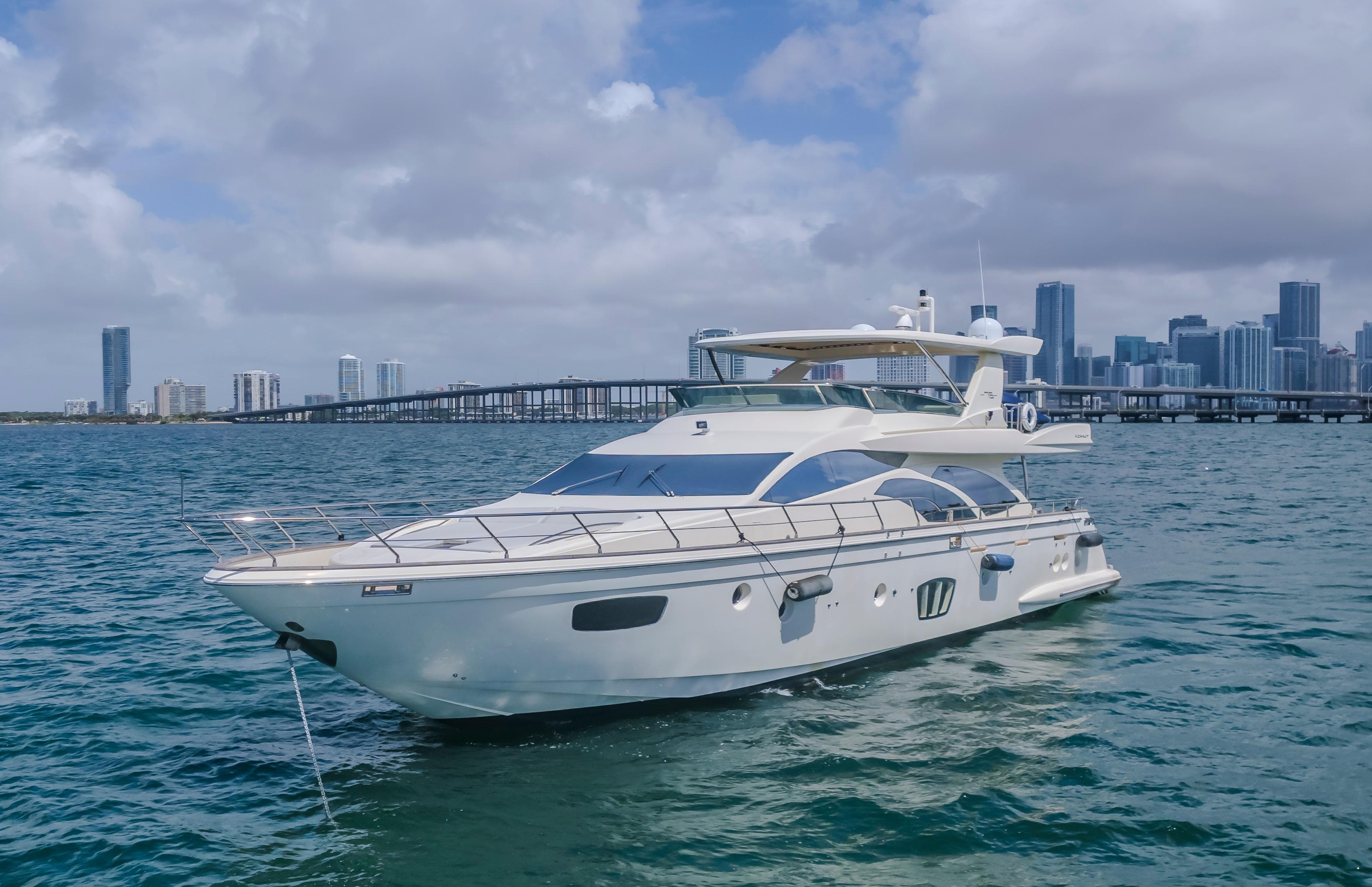 2008 Azimut Flybridge yacht on water with city skyline in background.