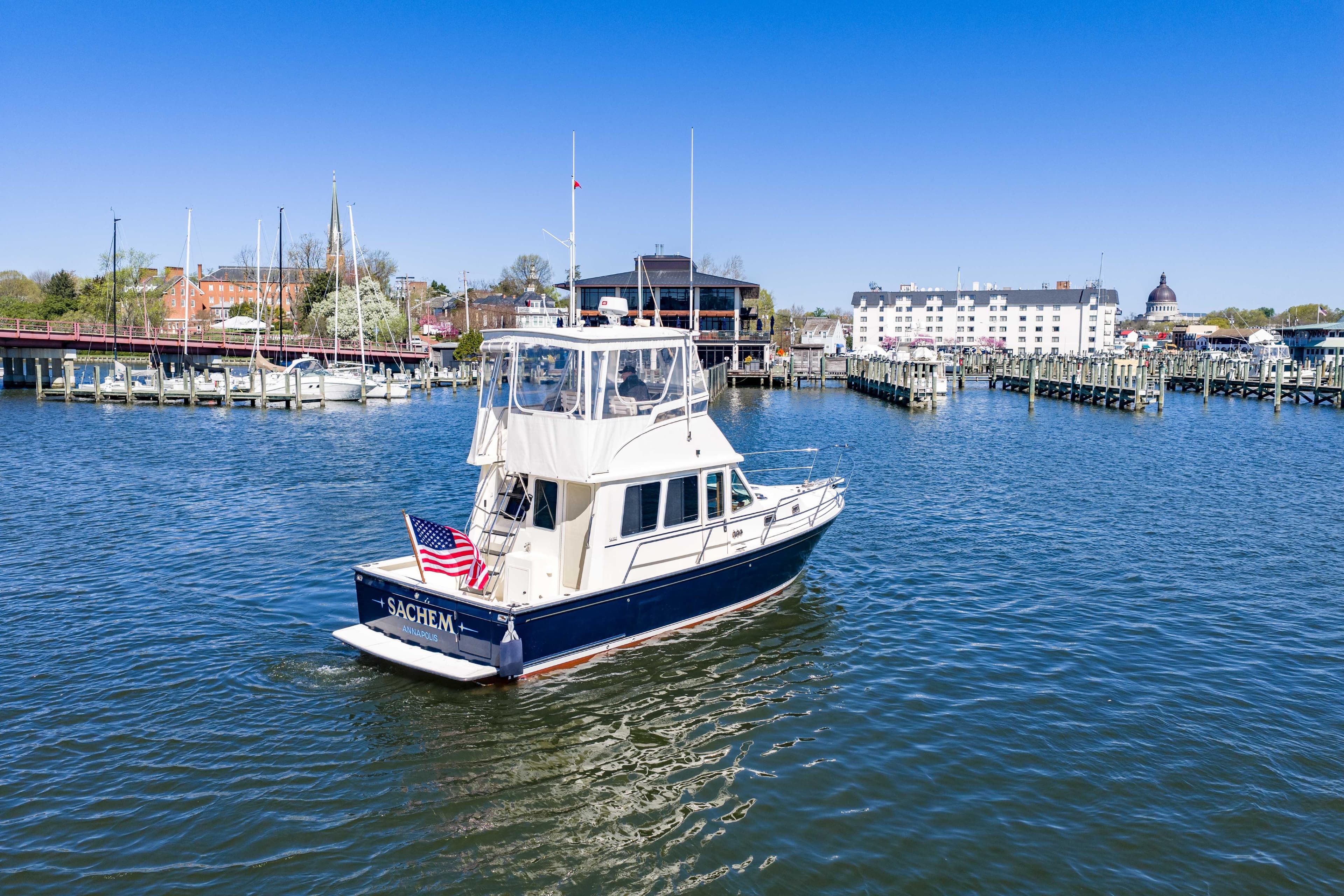 2006 Sabreline 36 Fly yacht cruising in a scenic marina with clear blue skies.