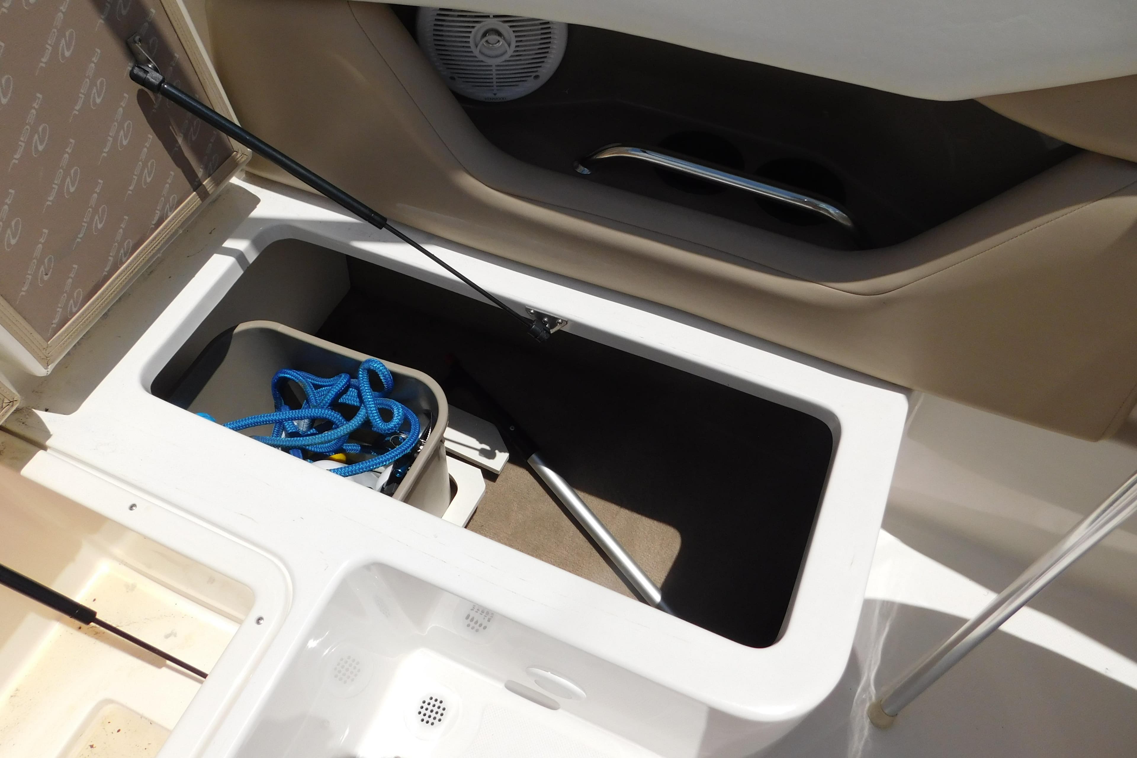 Storage compartment in a 2004 Regal 2250 LSC boat with blue rope and accessories.