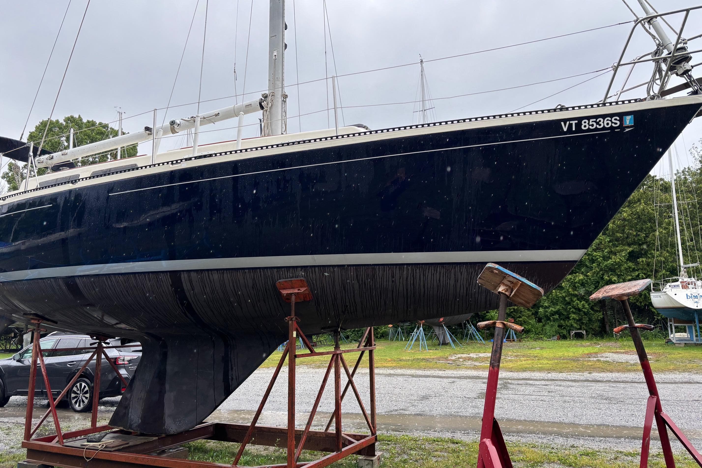 1979 Aloha 34 sailboat on stands, dark hull, parked outdoors.