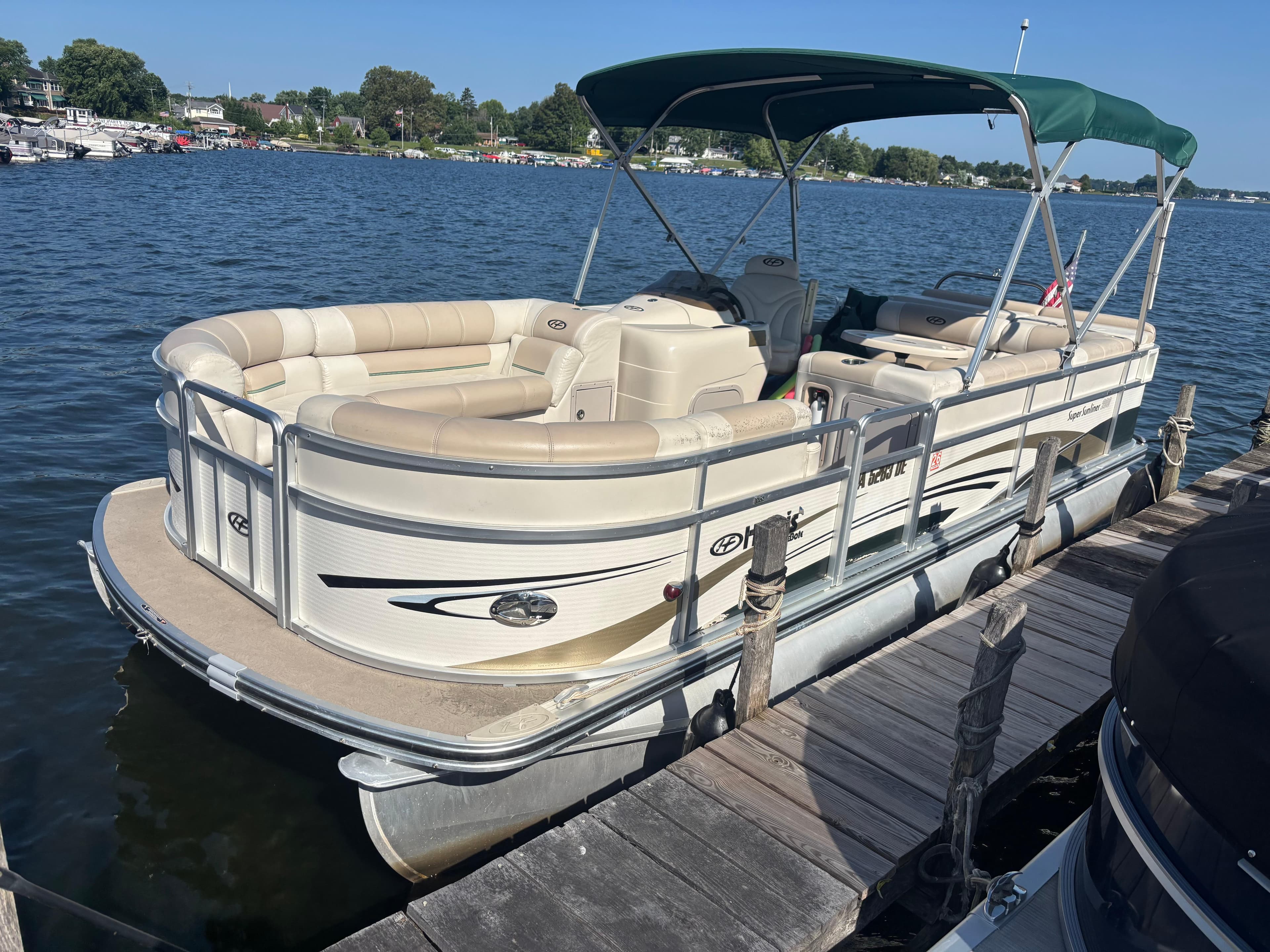 2010 Harris FloteBote 200 Super Sunliner pontoon boat docked on a sunny lake.