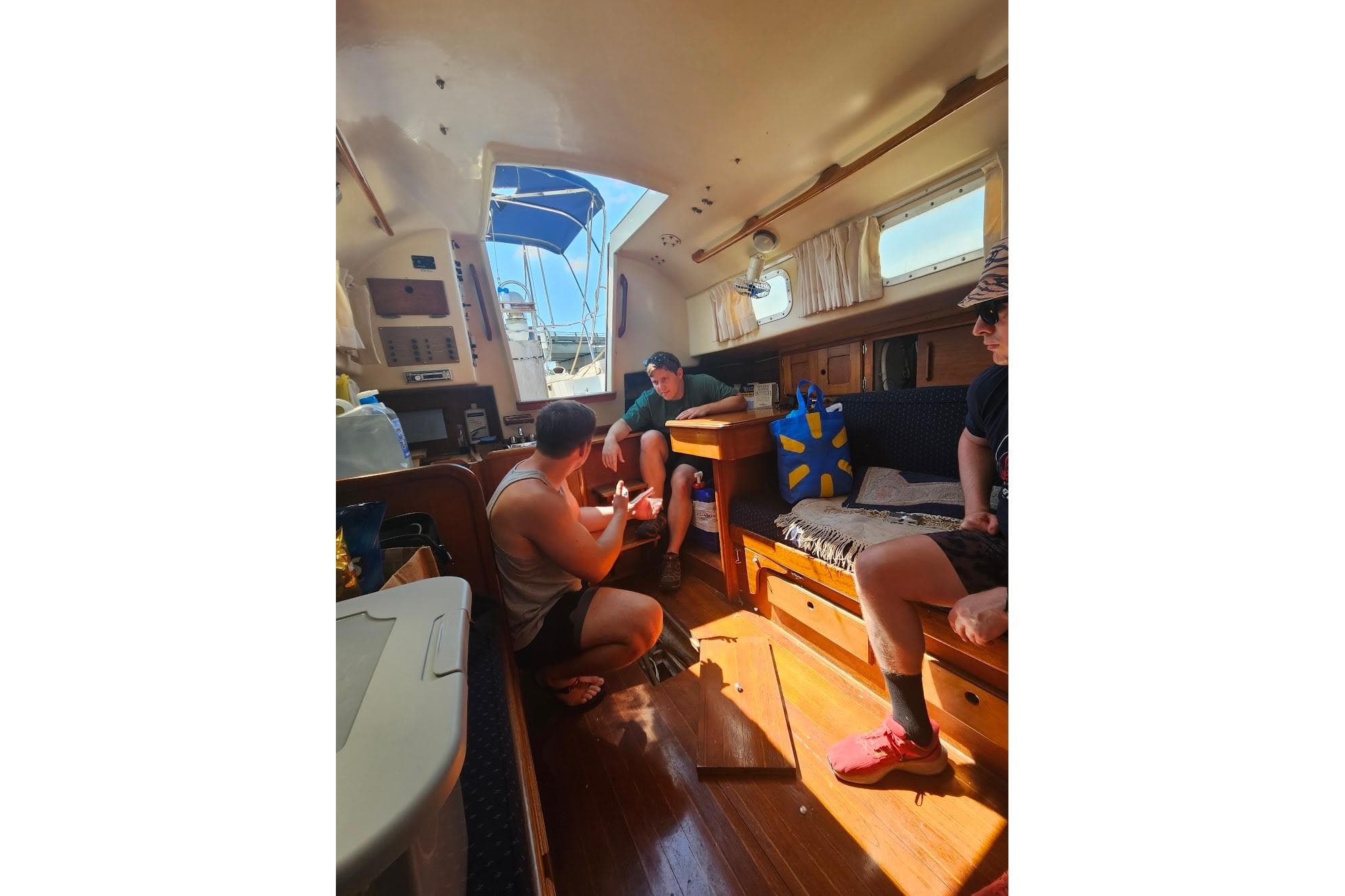 Interior of a 1978 Bristol 29.9 sailboat with people relaxing and chatting.