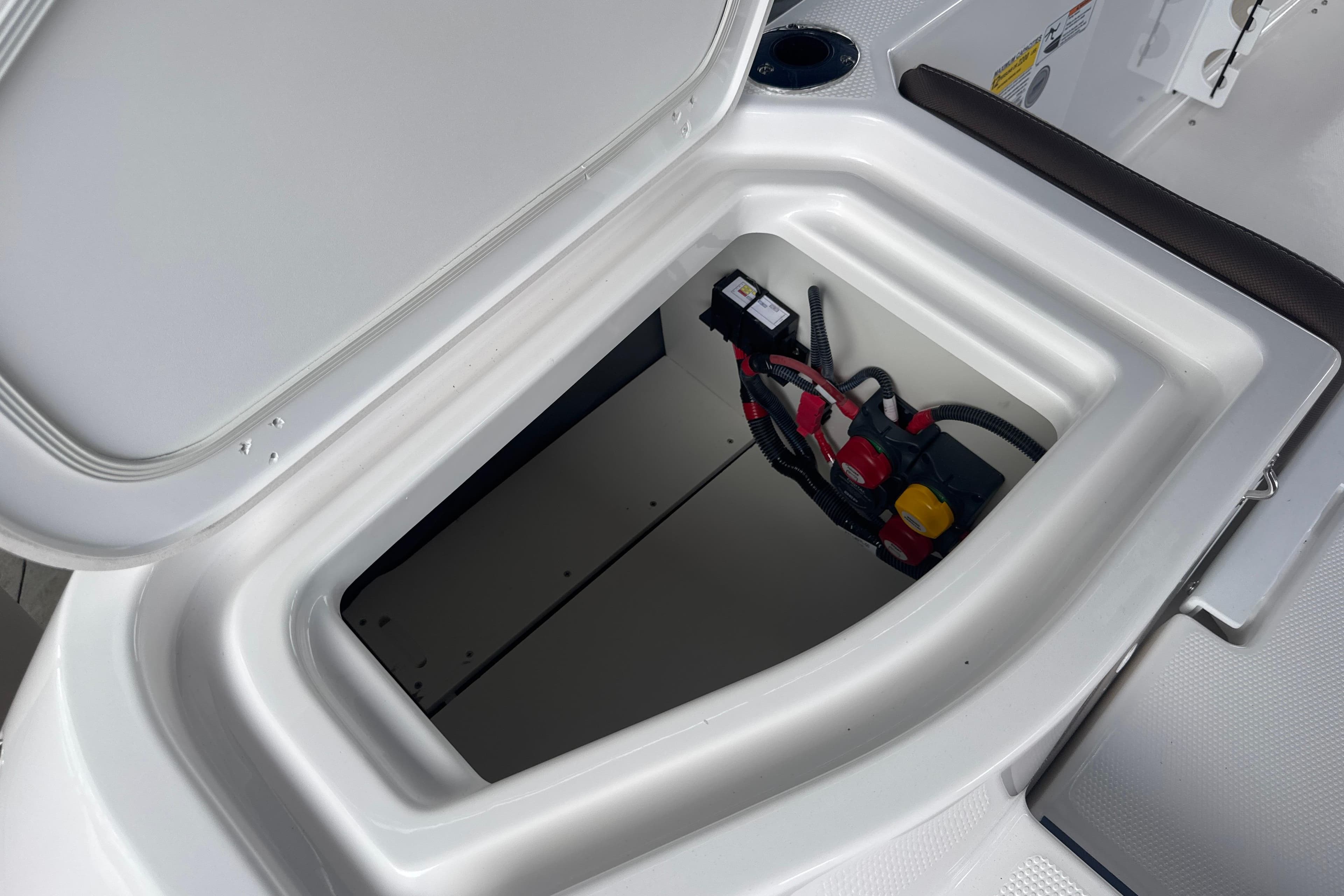 Open storage compartment in 2026 Yamaha Boats 252 FSH Sport, showcasing wiring and battery setup.