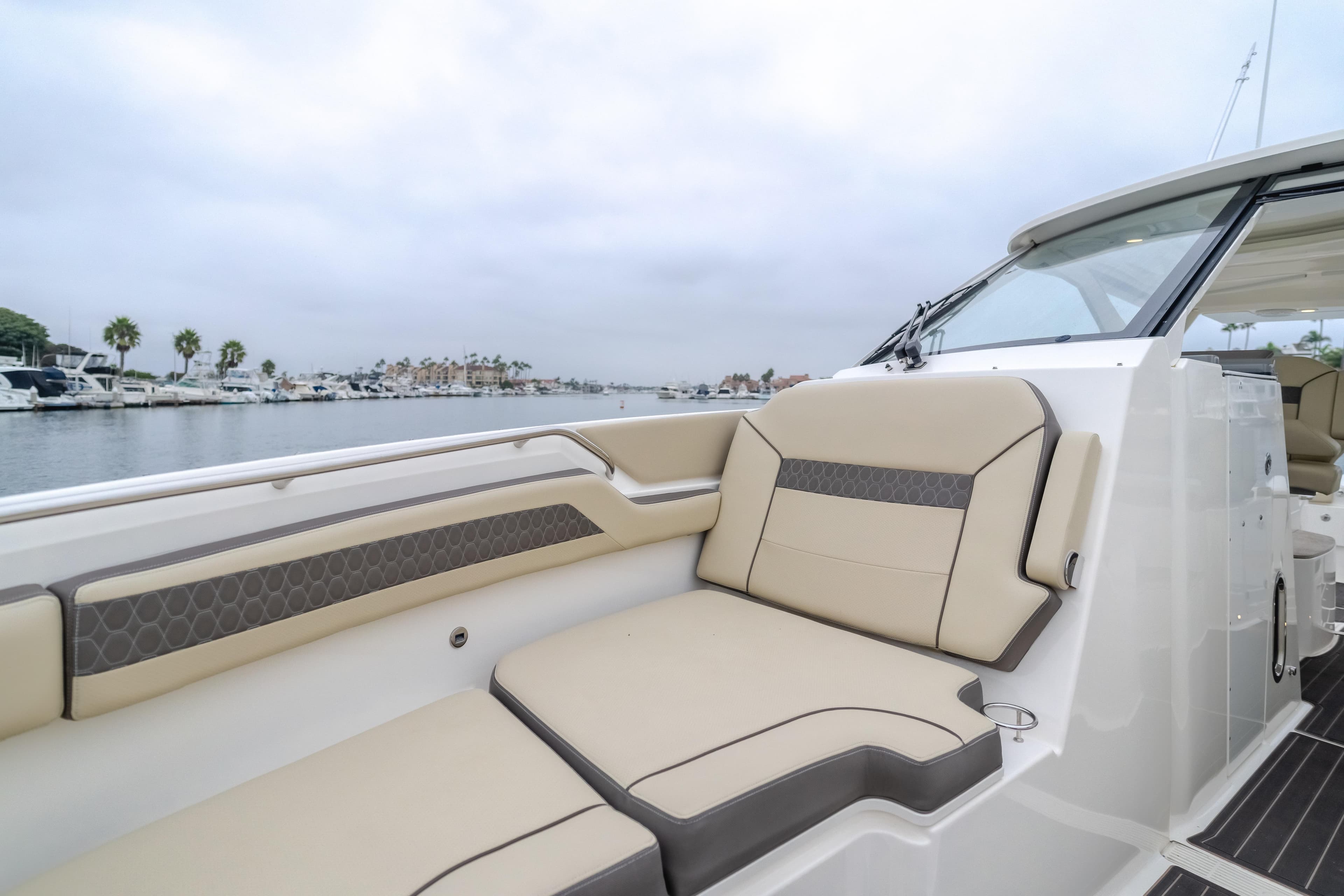 Luxurious 2018 Pursuit boat with beige seating, docked in a marina.