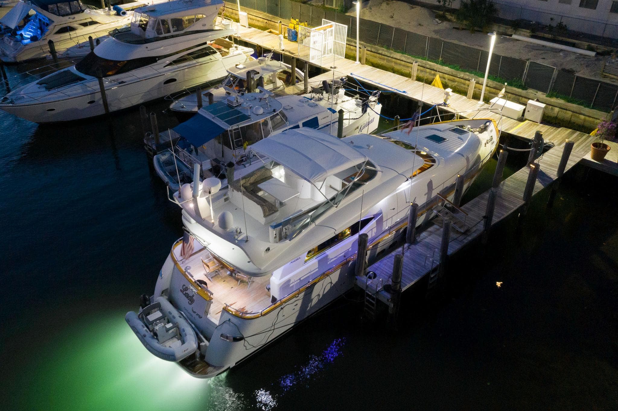 Luxurious 1997 Maiora FIPA 70' Flybridge yacht docked at night, illuminated by soft lights.