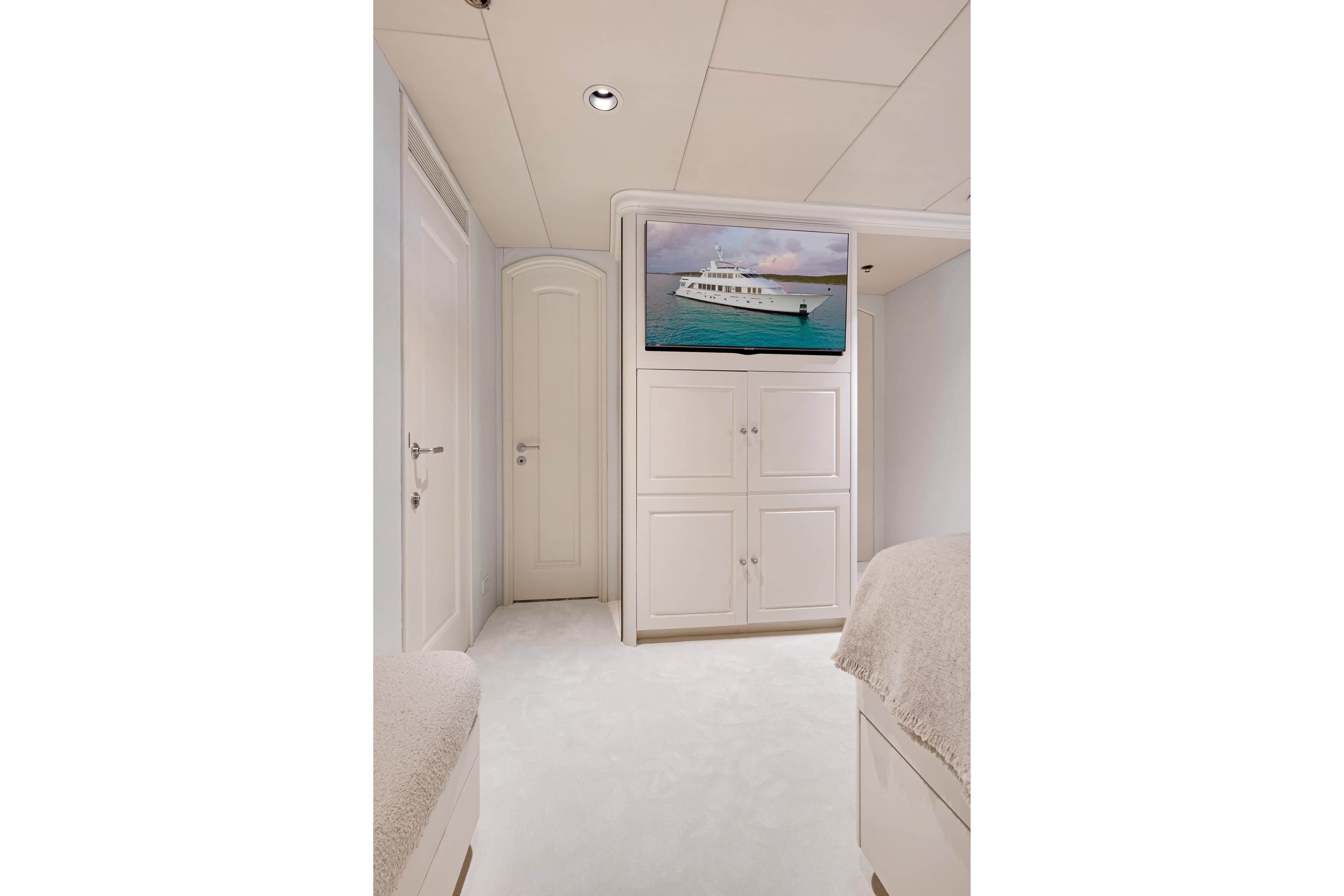 Luxurious interior of 1995 Christensen Tri-Deck yacht with elegant white cabinetry and TV.
