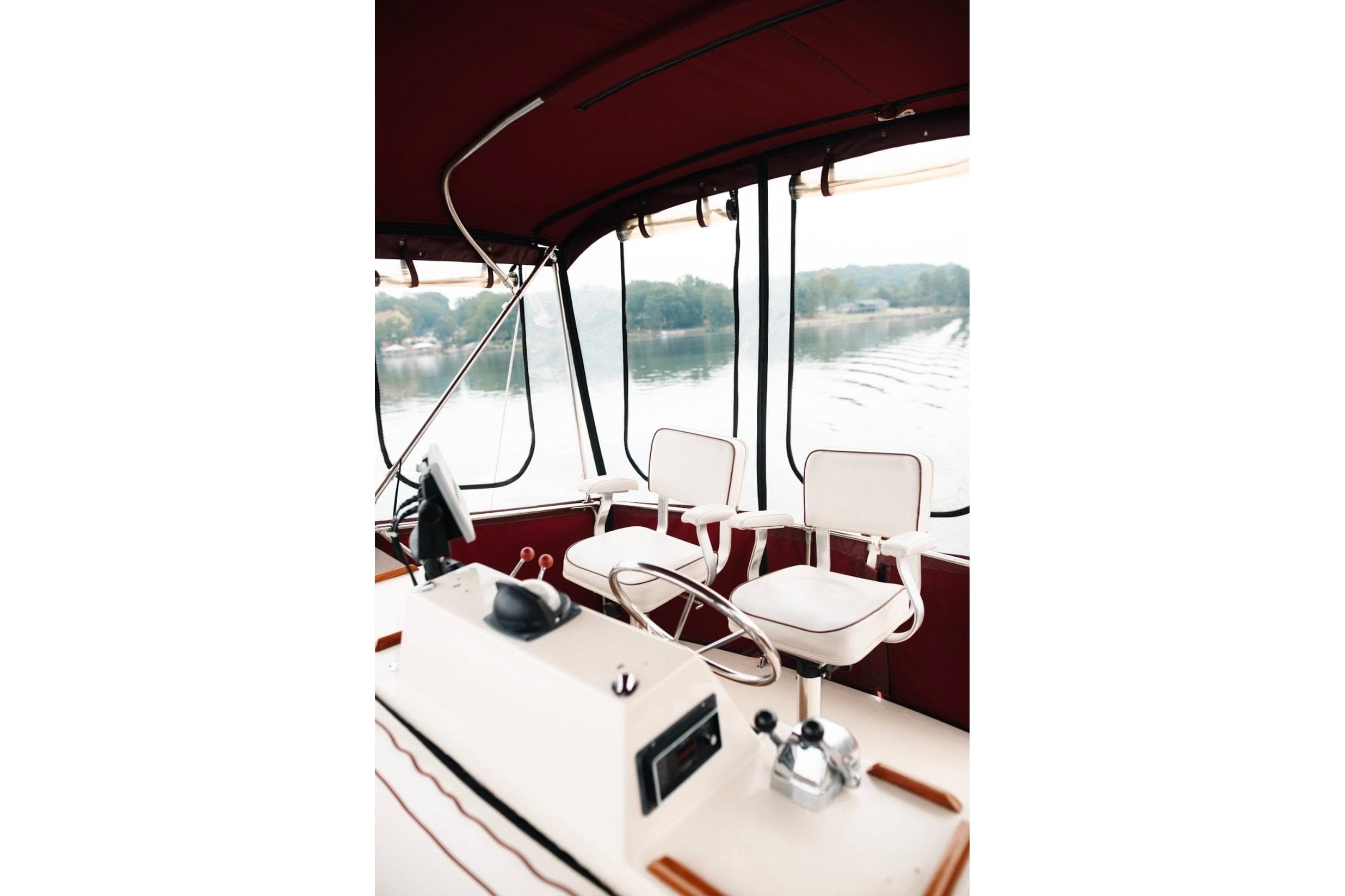 Interior of 1982 Trojan F-36 Convertible boat with helm and white seating.