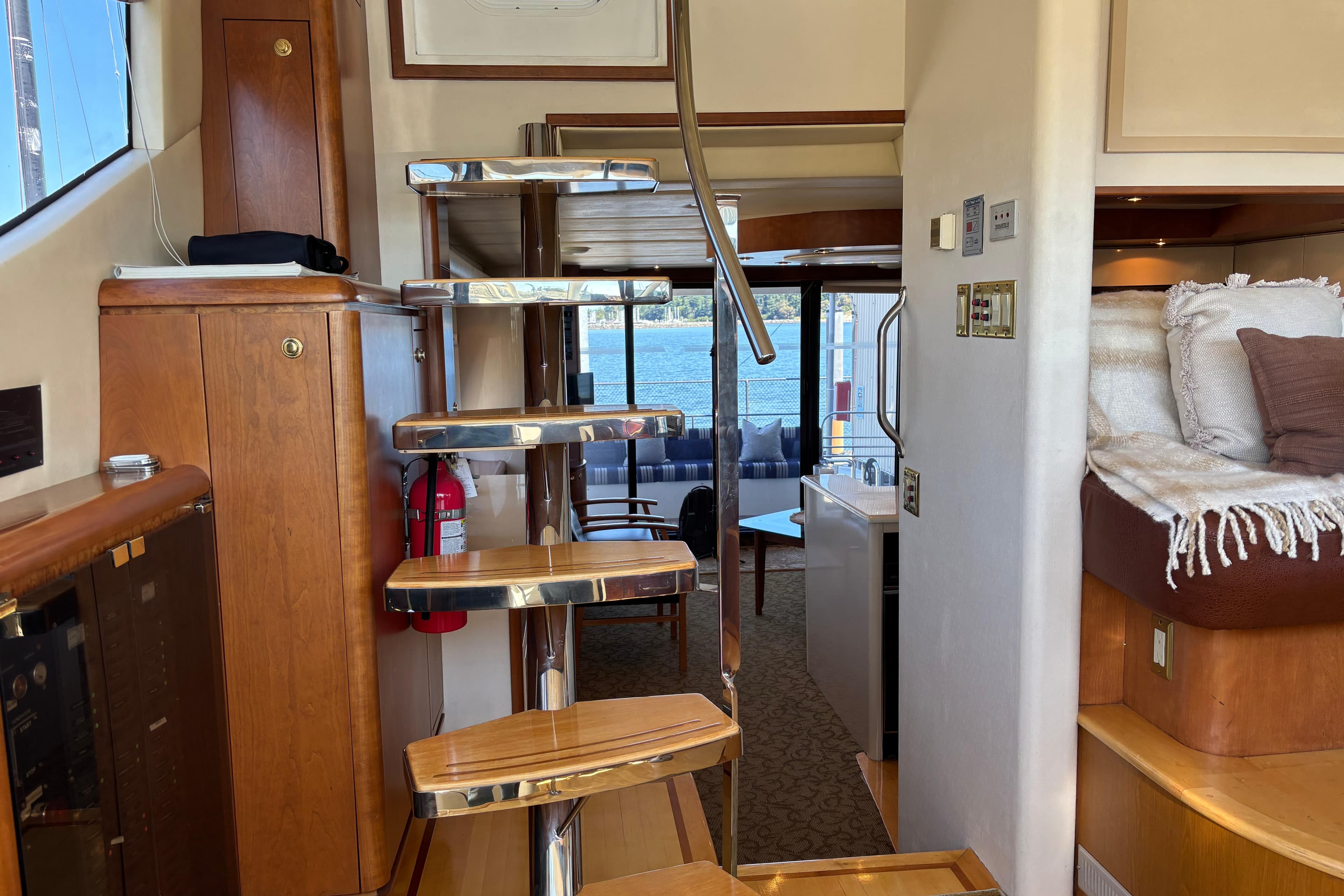 Interior of a 1996 Queenship yacht with wooden stairs and cozy seating area.