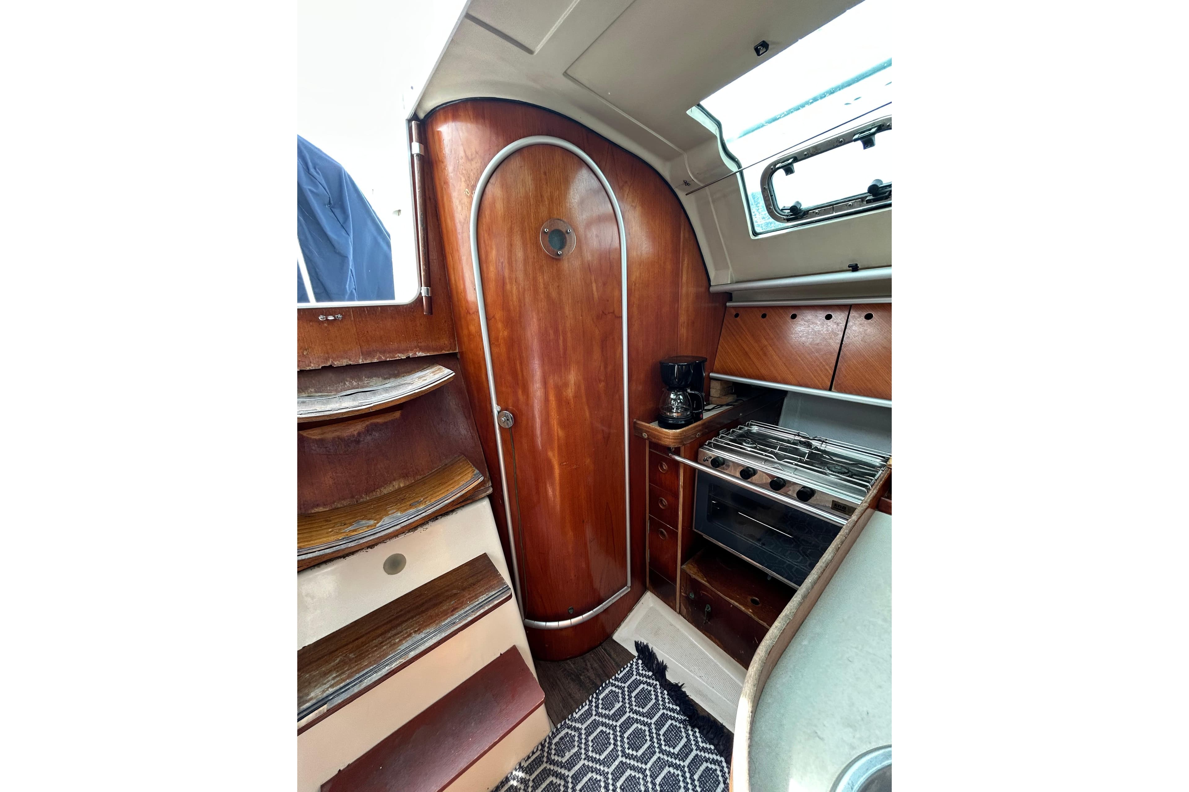 Interior of 1992 Beneteau First 35s5 sailboat with wooden cabinetry and compact kitchen.