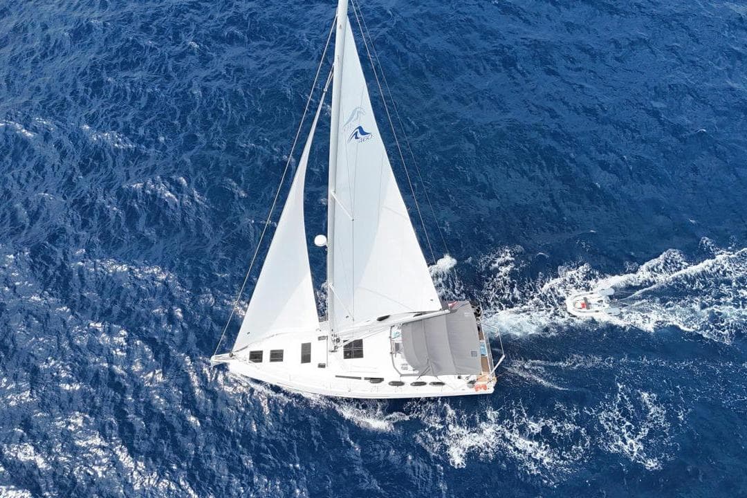 Aerial view of 2023 Hanse 460 sailboat navigating deep blue ocean waters.