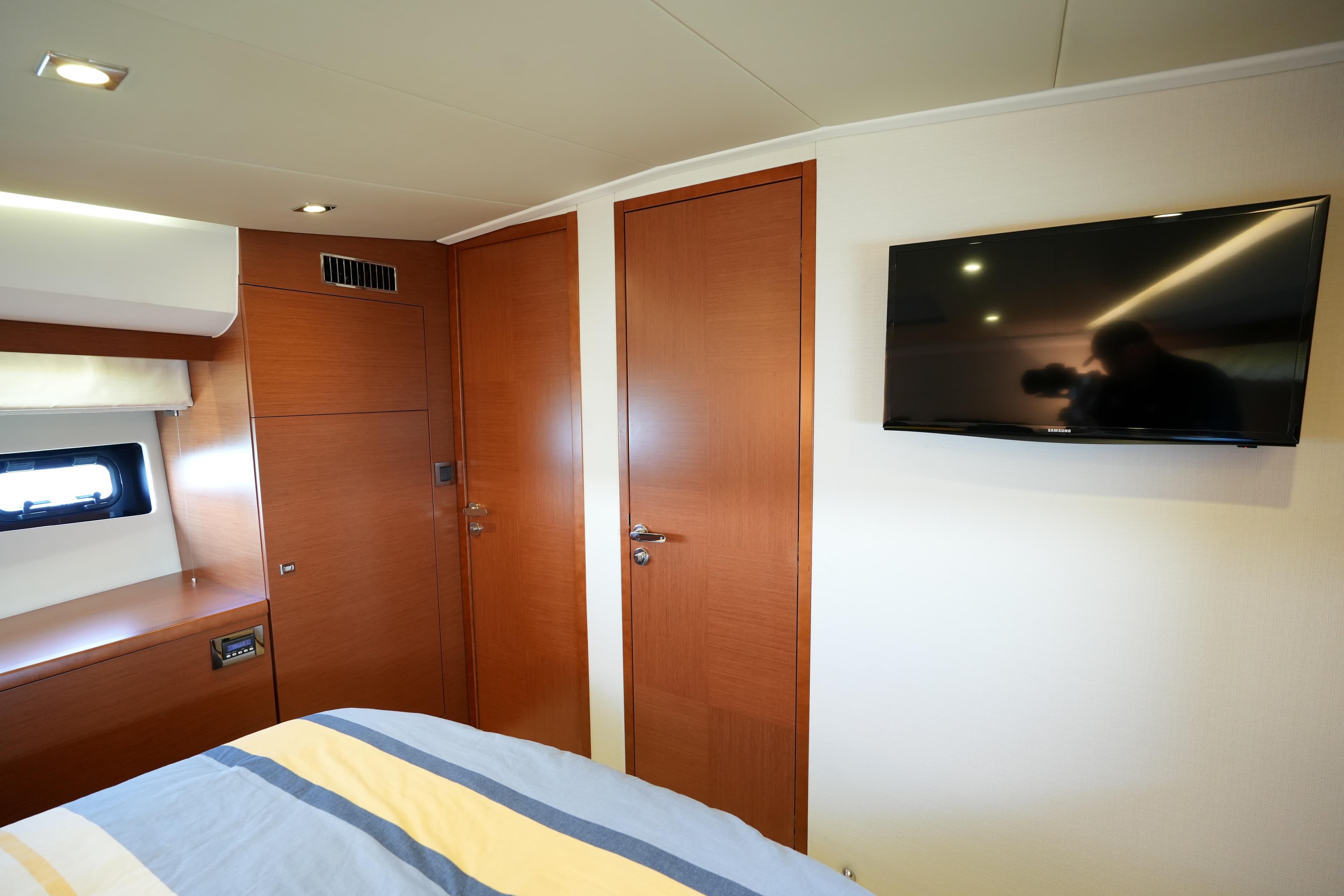 Luxurious cabin interior of 2015 Prestige 500S yacht with wood paneling and mounted TV.