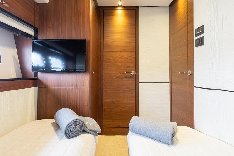 Luxurious cabin interior of 2017 Princess 75 Motor Yacht with twin beds and TV.
