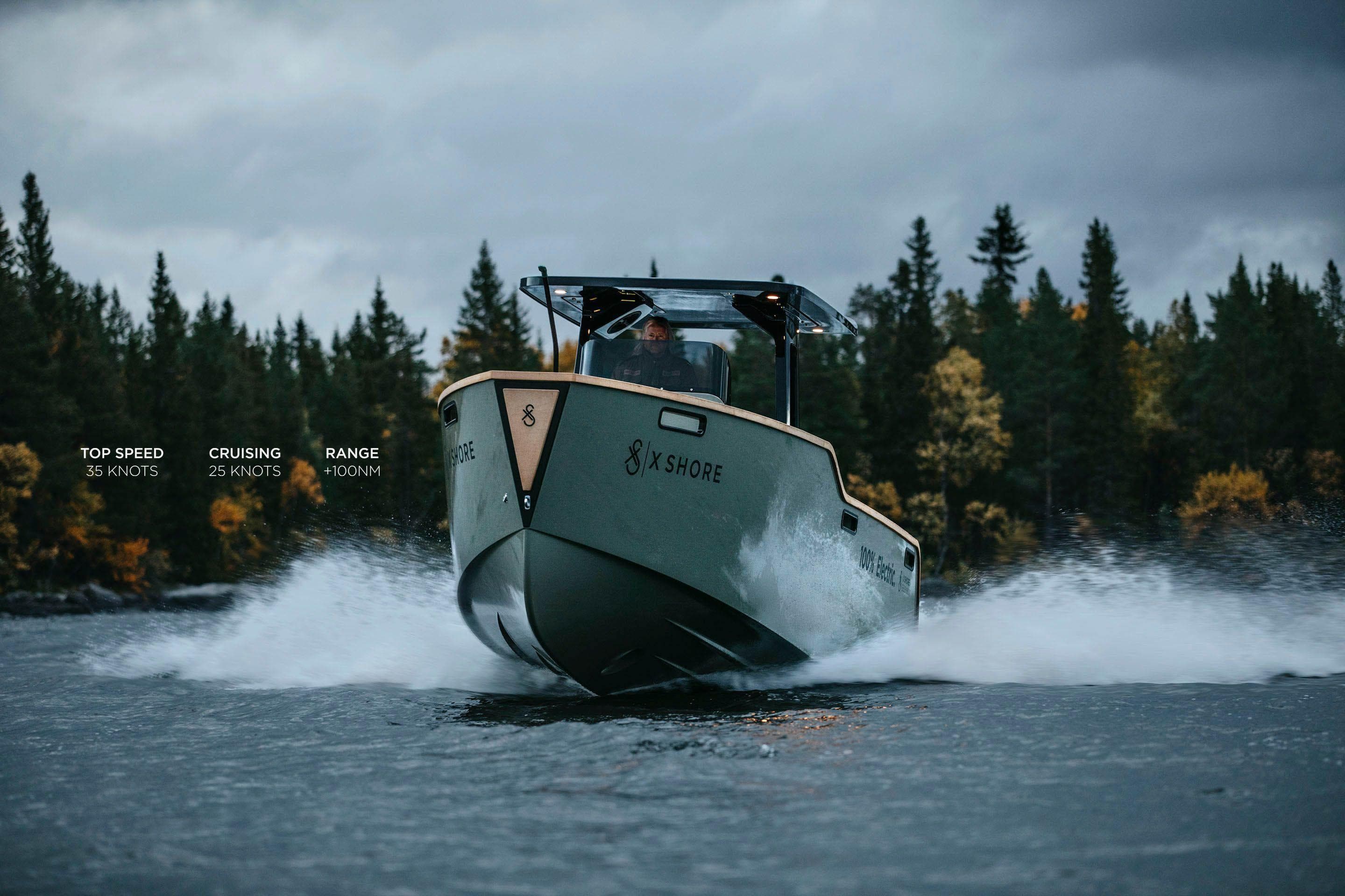 2023 X Shore Eelex 8000 electric boat cruising on a lake with forest backdrop.