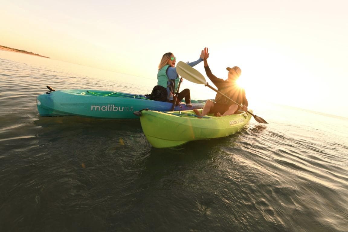 Two people kayaking on Ocean Kayak Malibu 11.5 at sunset, 2023 model.