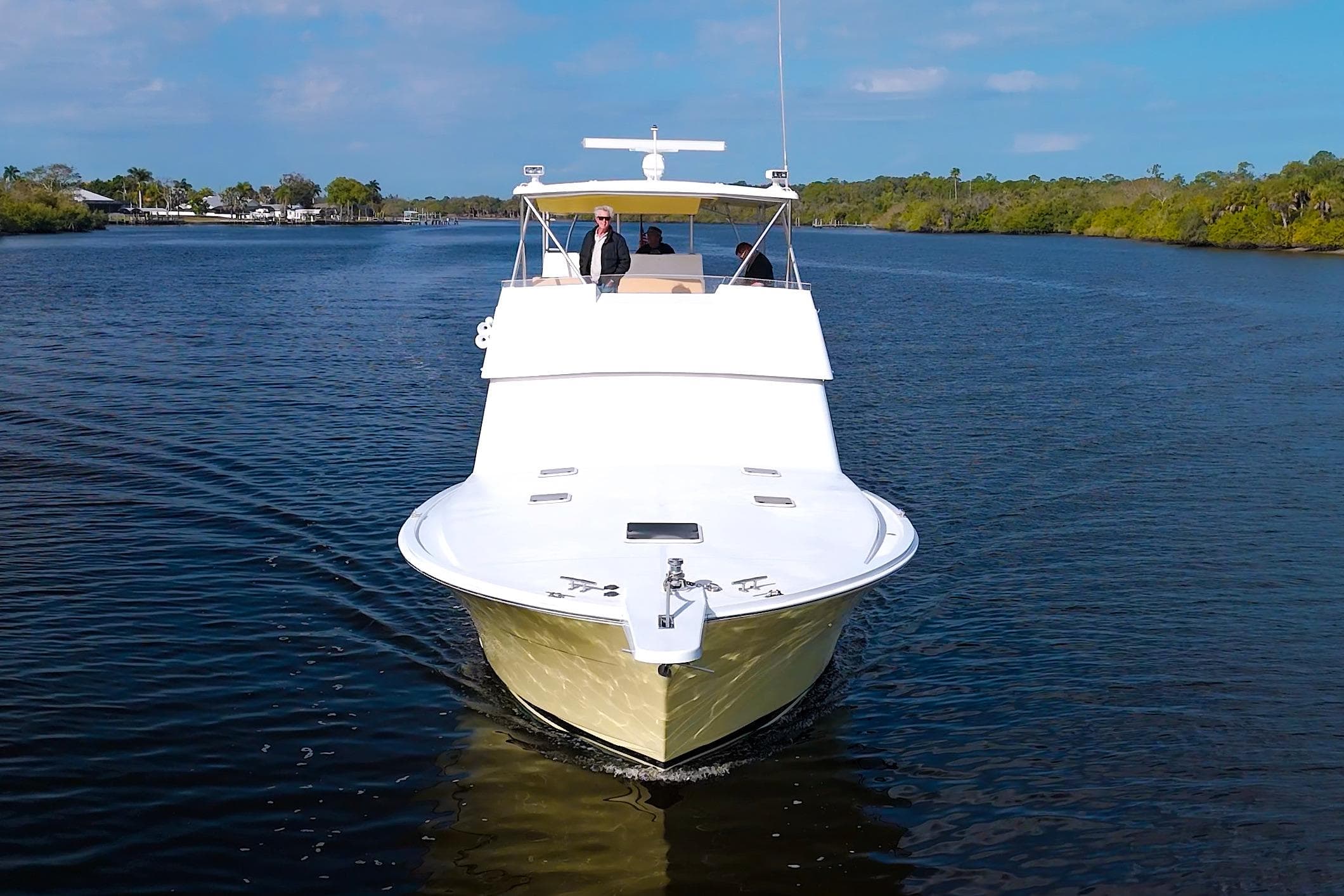 1990 Viking 53 Convertible yacht cruising on a serene river under a clear blue sky.