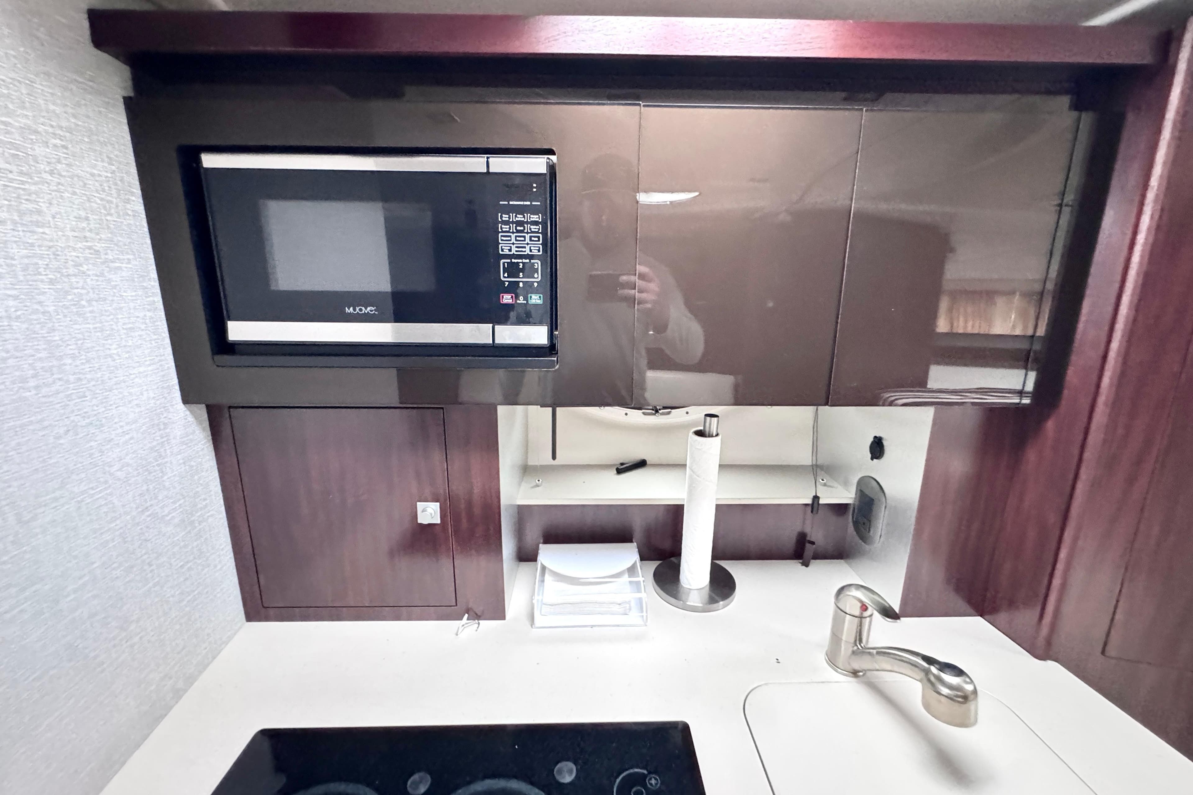 Modern kitchen area in a 2019 Monterey 335 Sport Yacht with microwave and sleek cabinetry.